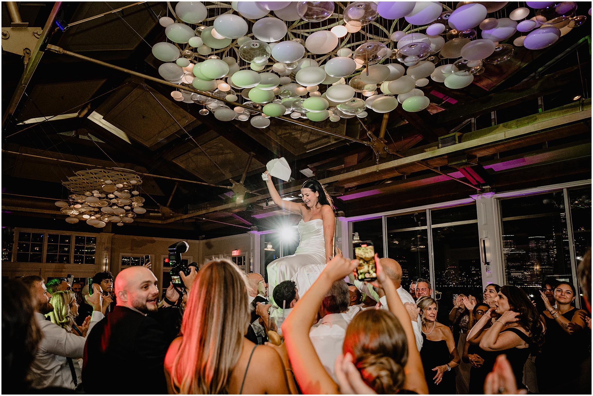 guests lift up bride during wedding reception at the Liberty House while she twirls napkin