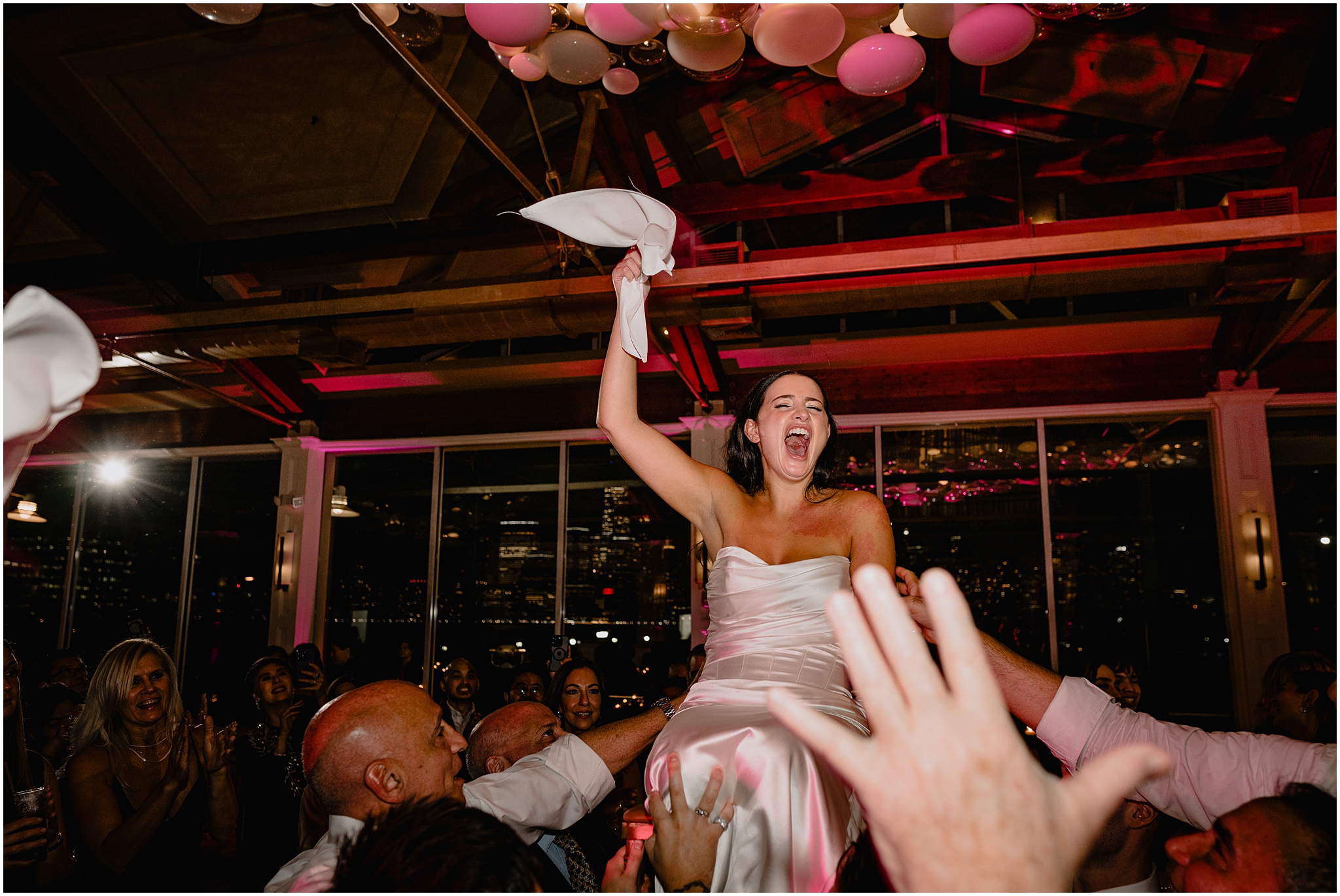 bride twirls napkins during wedding reception while being lifted in a chair
