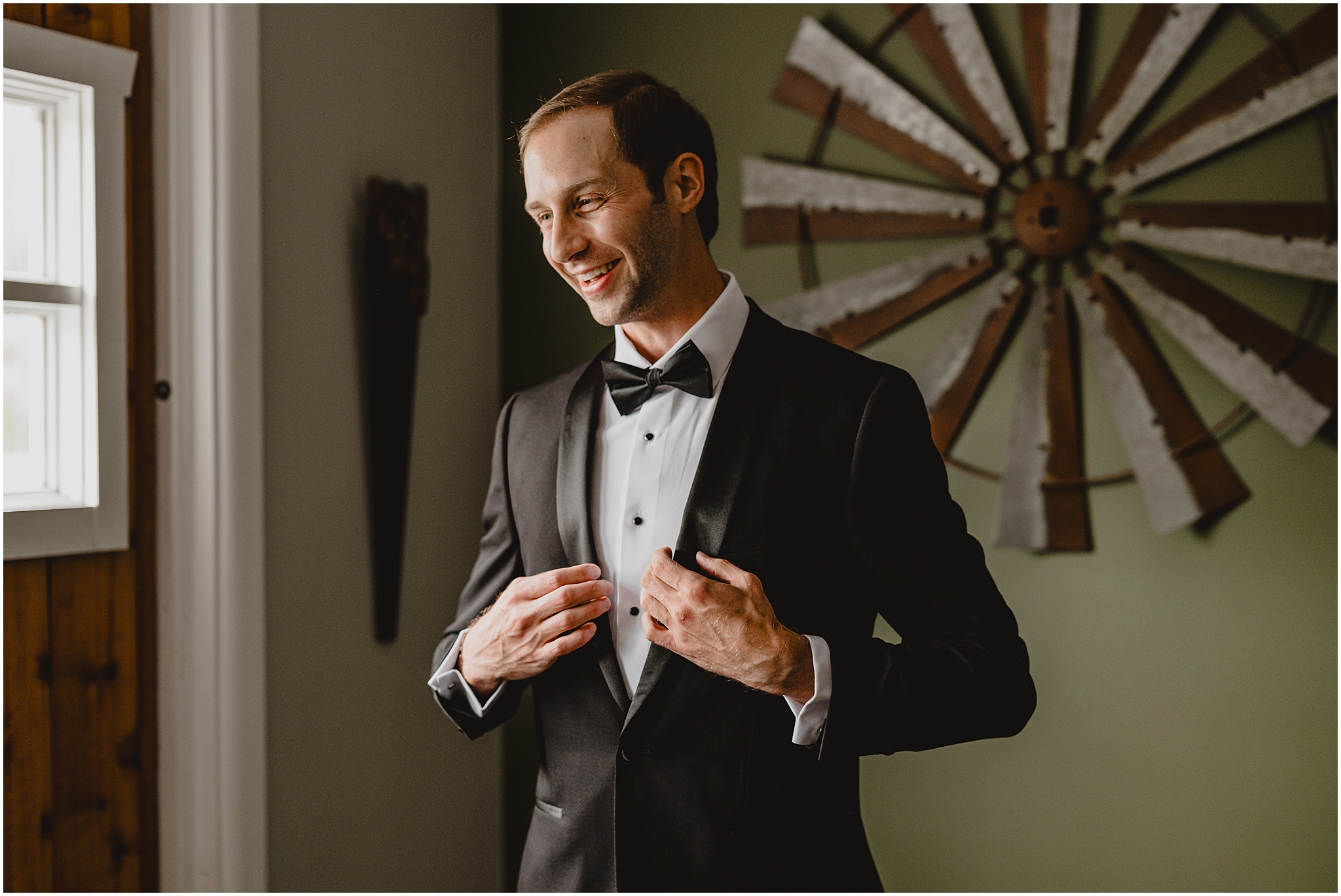 groom grins preparing for wedding day in black suit jacket