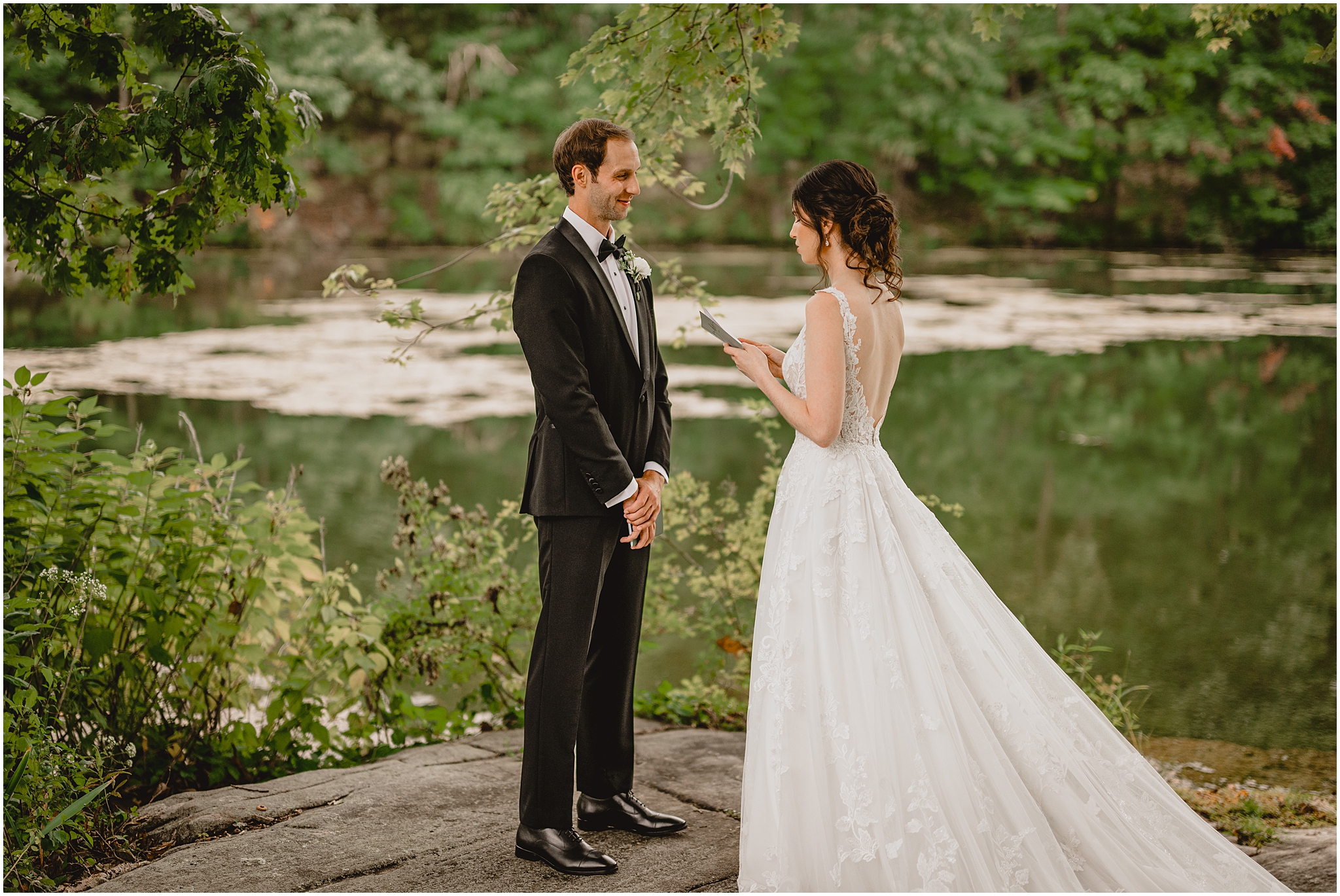 bride reads vows to groom on flat rock by pond at the Reserve at Perona Farms