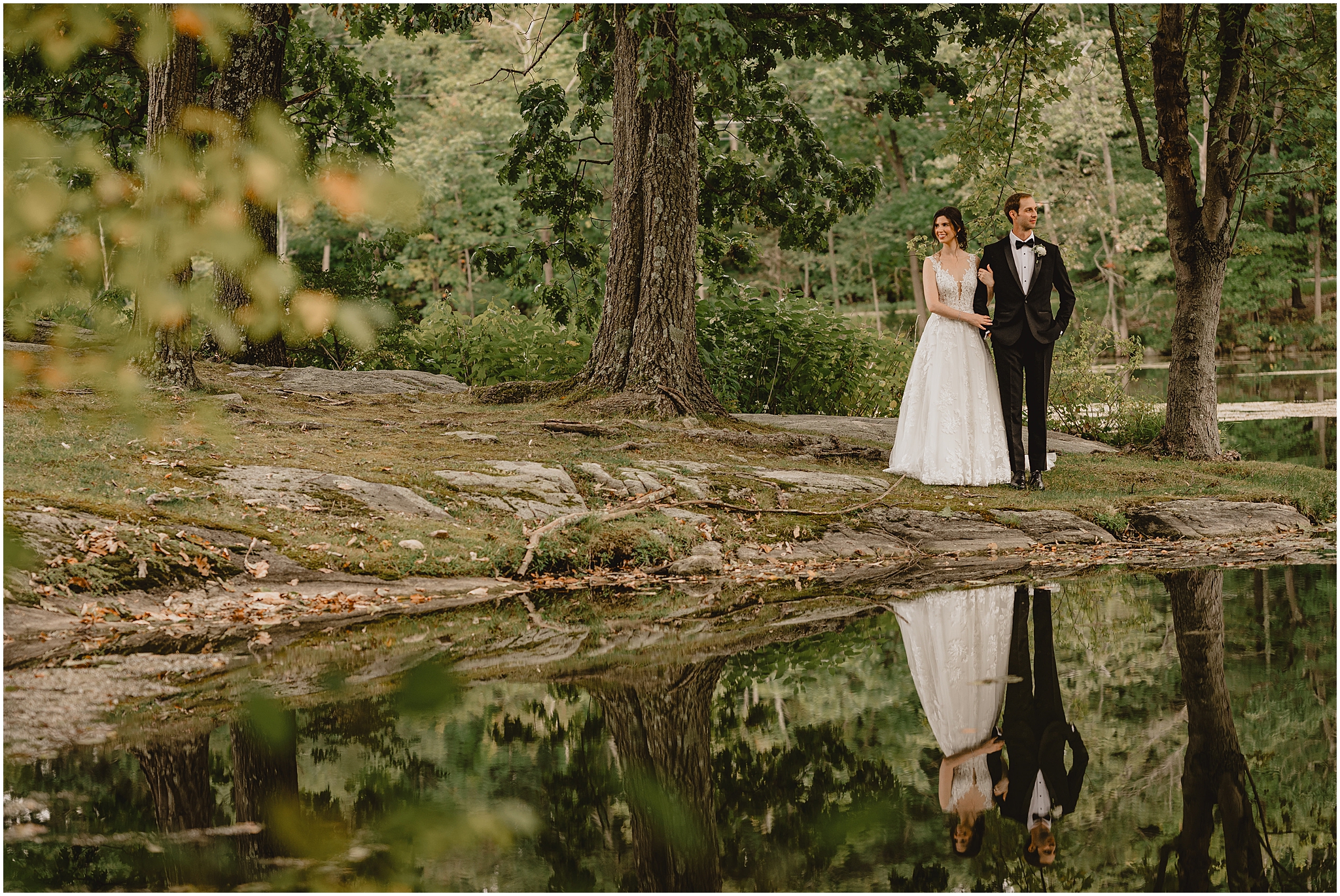 bride holds groom's arm looking away from by pond at the Reserve at Perona Farms