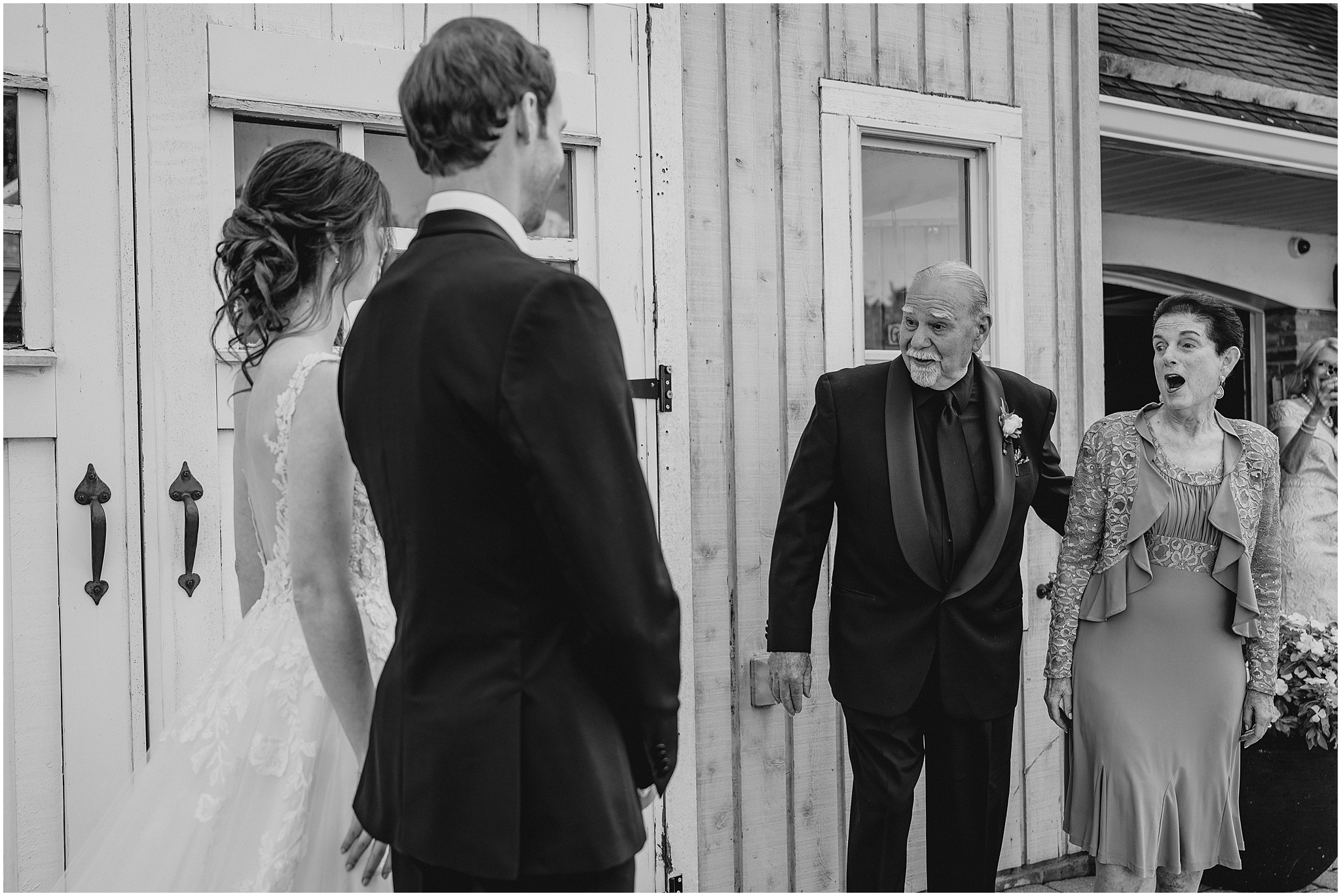 bride and groom have first look with family members outside barn at the Reserve at Perona Farms