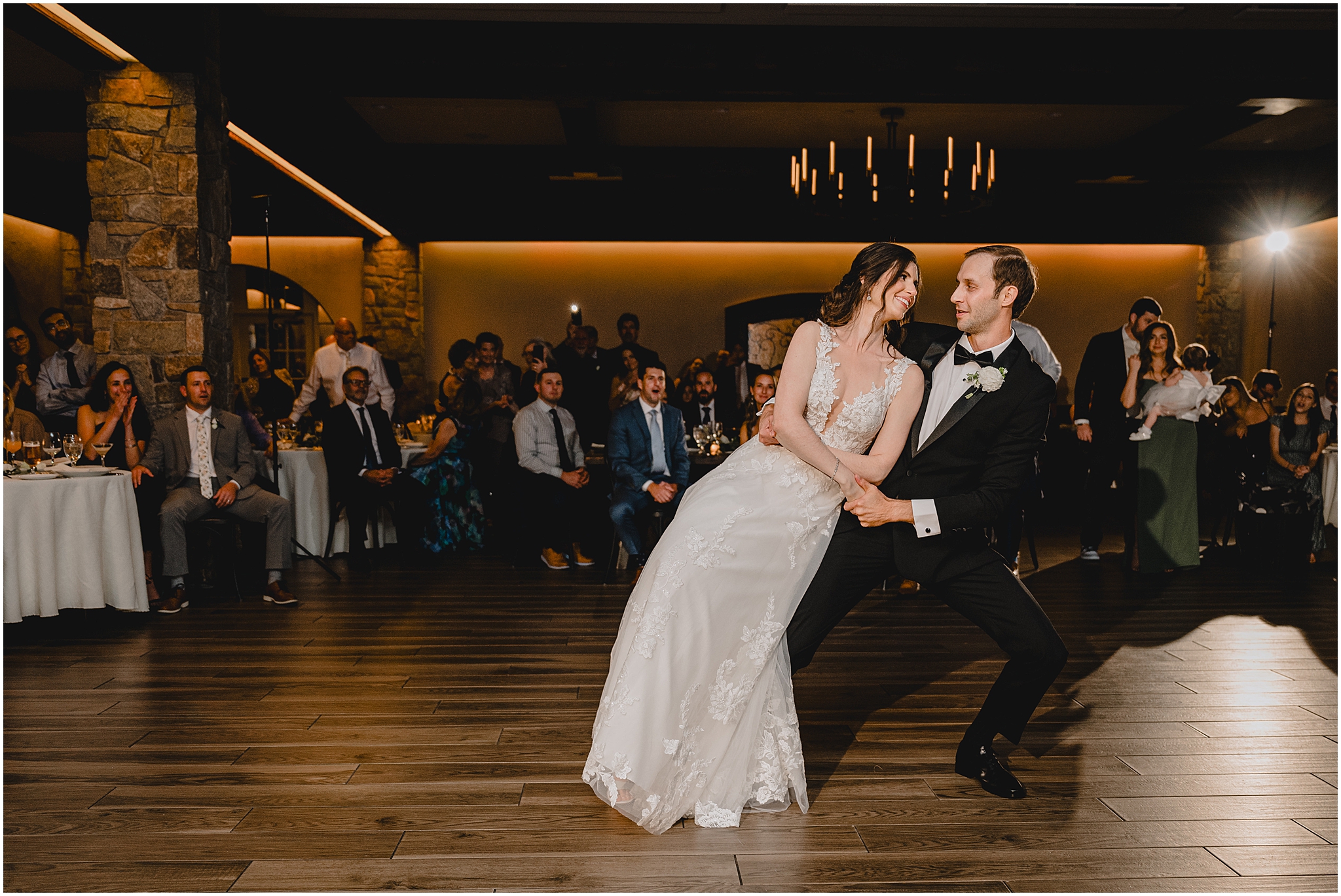 groom leans with bride on his hip during first dance at wedding reception at Perona Farms