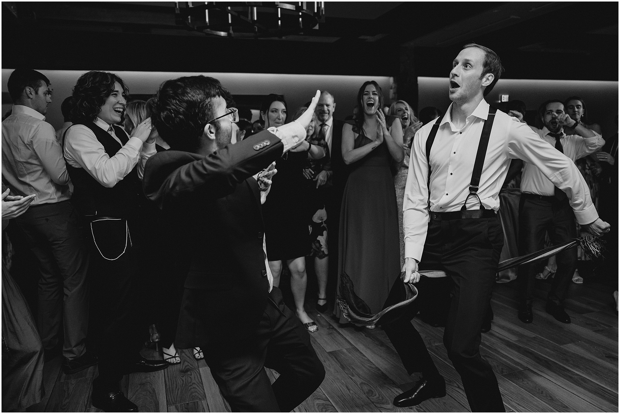 groom dances with scarf between his legs with guests during reception at the Reserve at Perona Farms