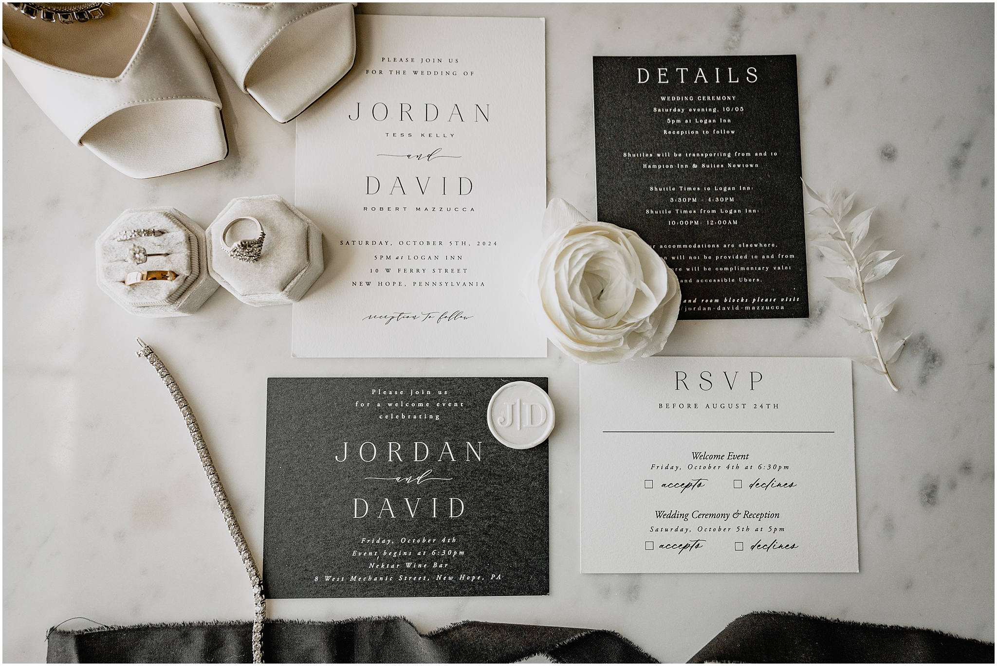 black and white invitation suite with bride's ivory shoes and white flowers on marble table at The Logan Inn