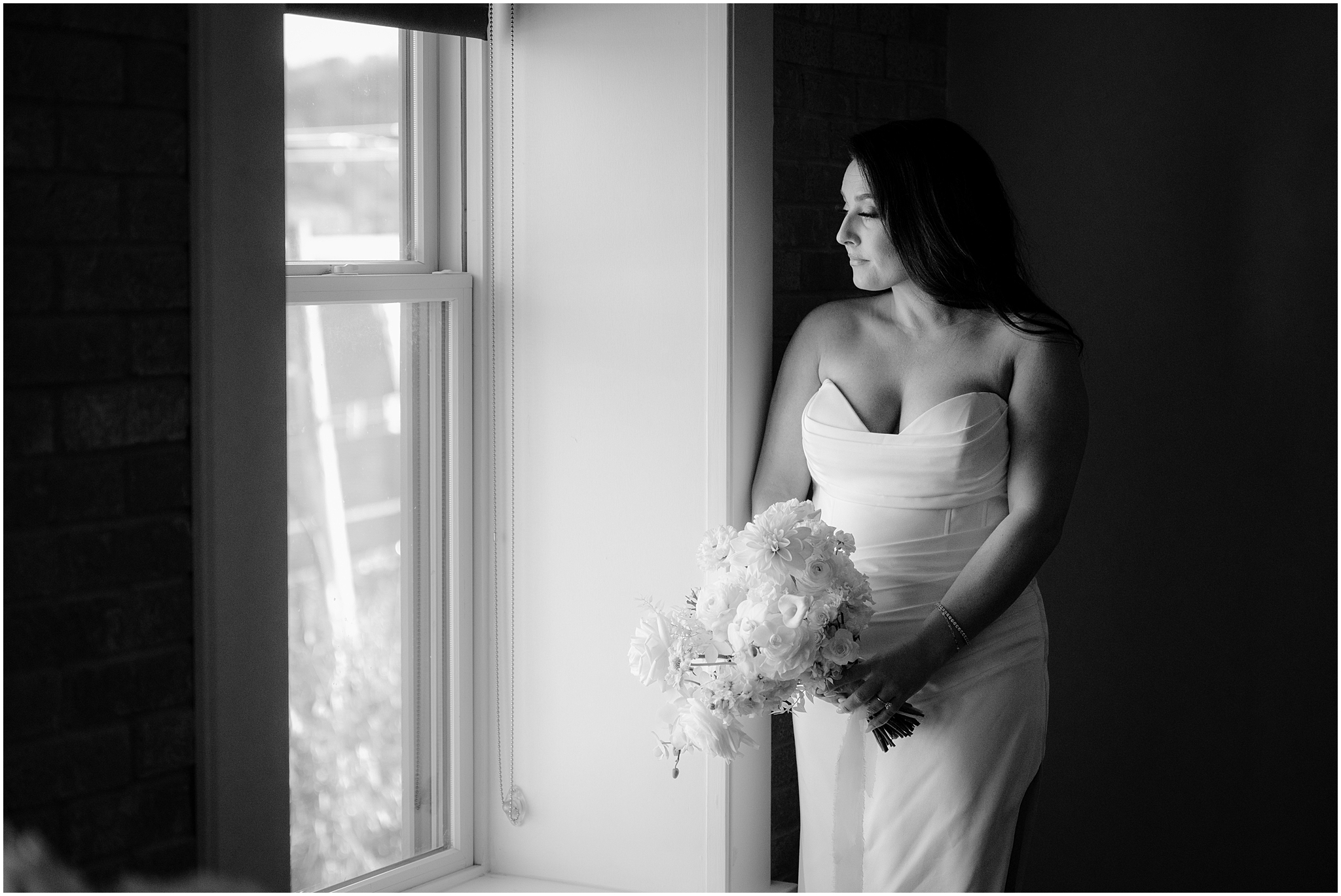 bride looks out window at The Logan Inn in strapless wedding gown