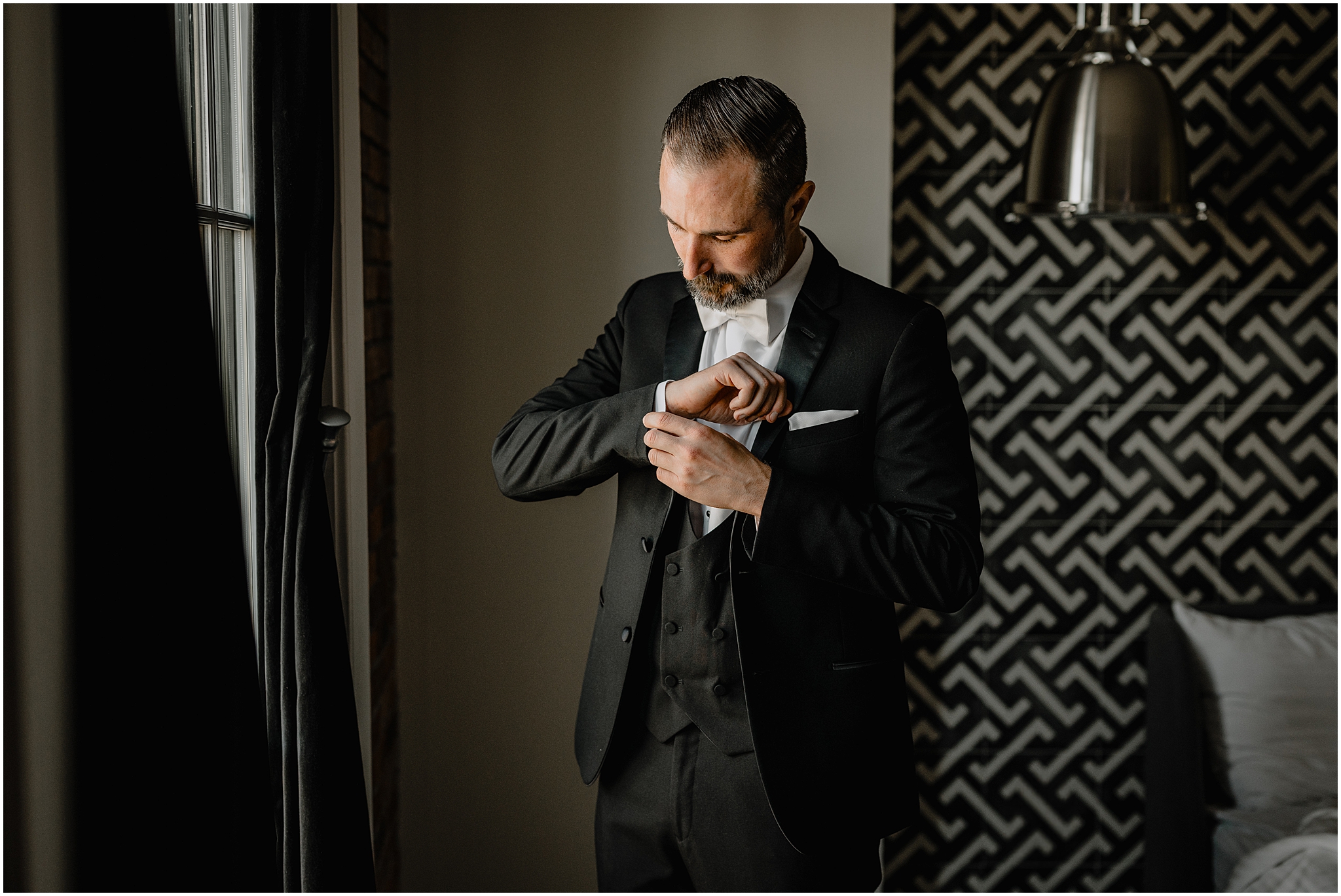 groom adjusts cufflinks in the groom's suite at The Logan Inn