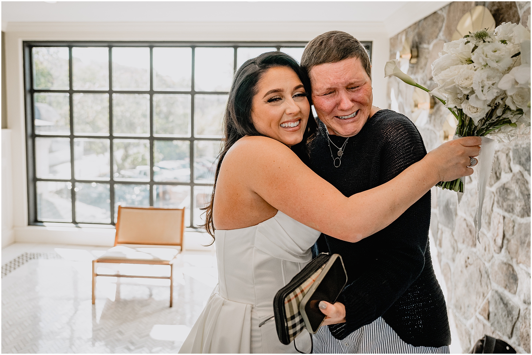 bride and family member hug while they cry inside the lobby of The Logan Inn