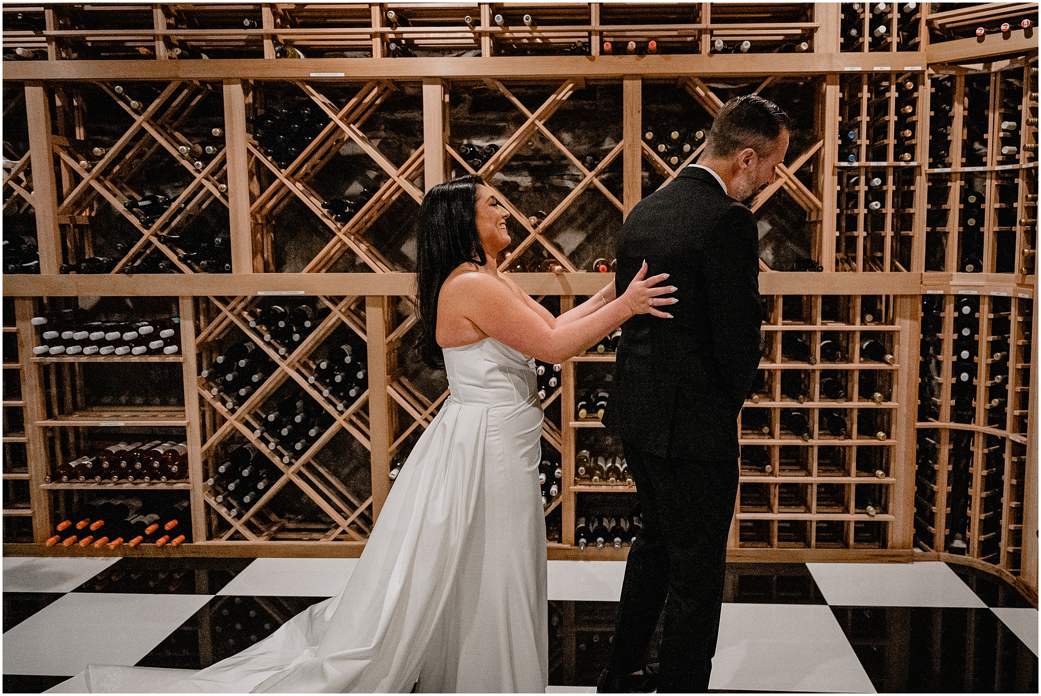 bride reaches for groom in wine cellar of The Logan Inn during first look