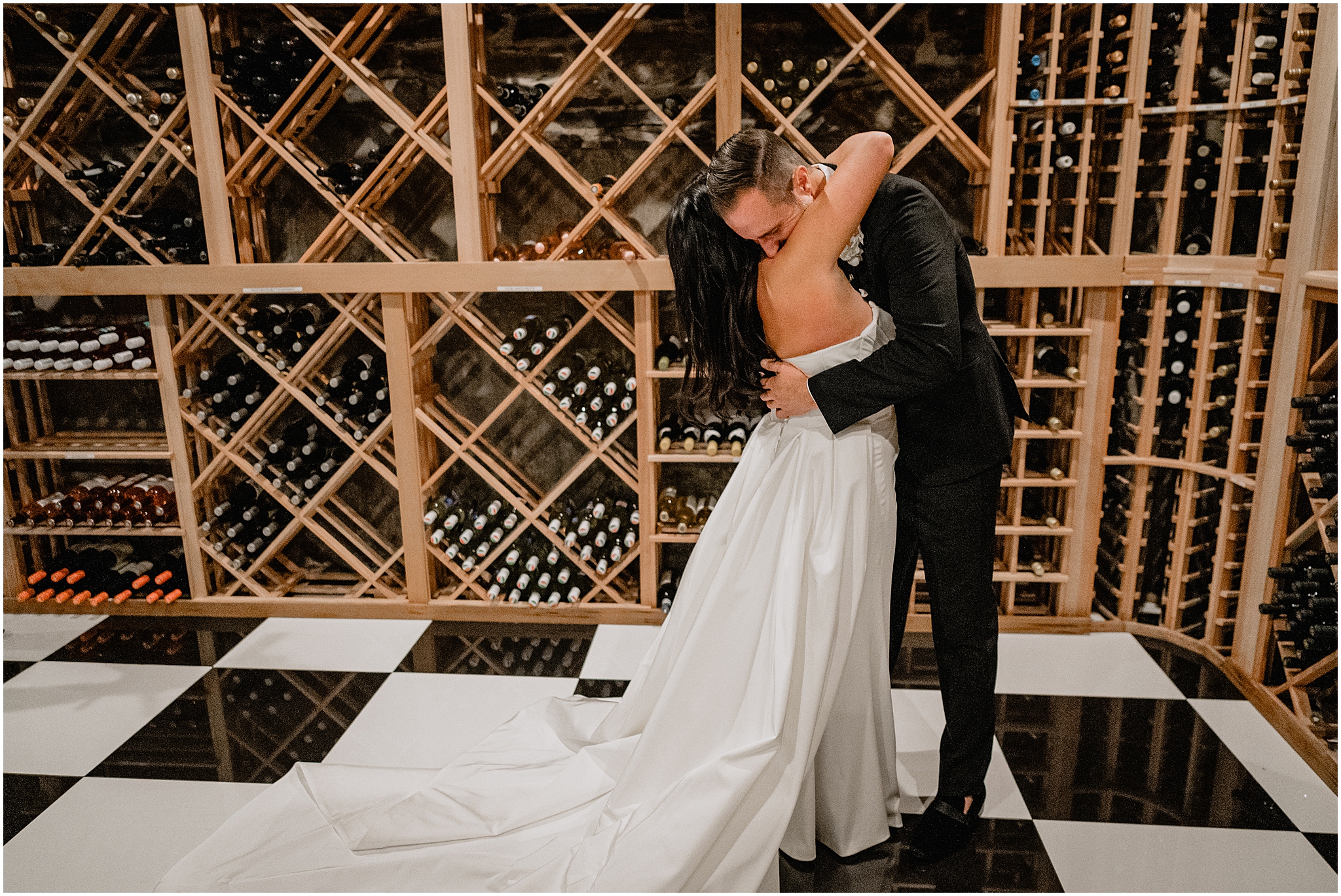 bride and groom hug in front of display of wine bottles in cellar at The Logan Inn