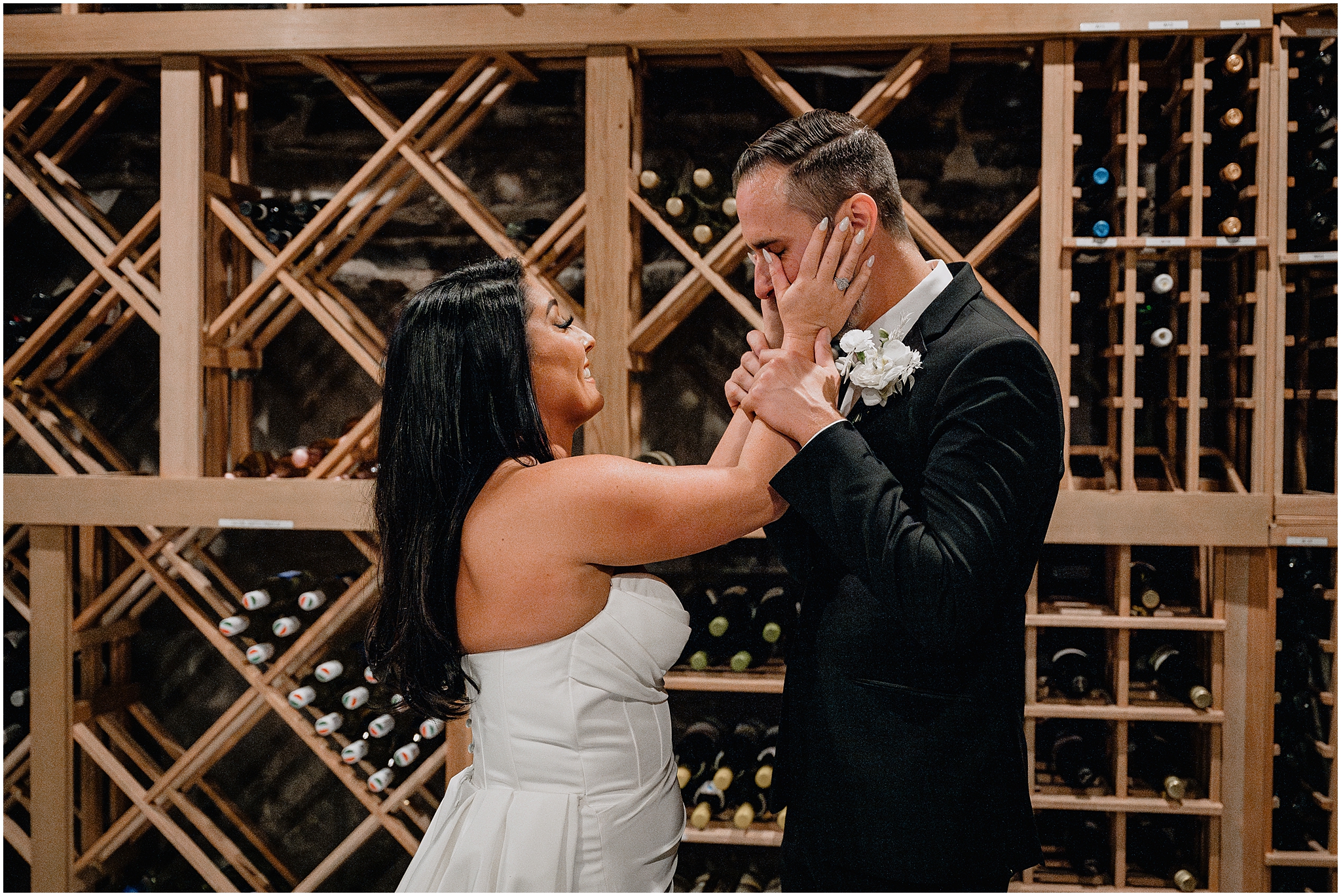bride wipes tears from groom's face during first look in wine cellar of The Logan Inn