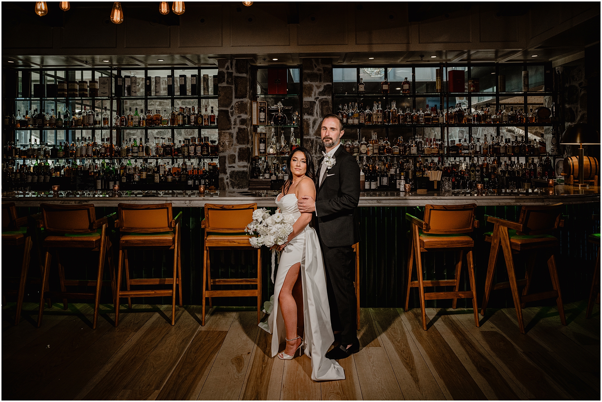 groom hugs bride from behind in front of bar at The Logan Inn