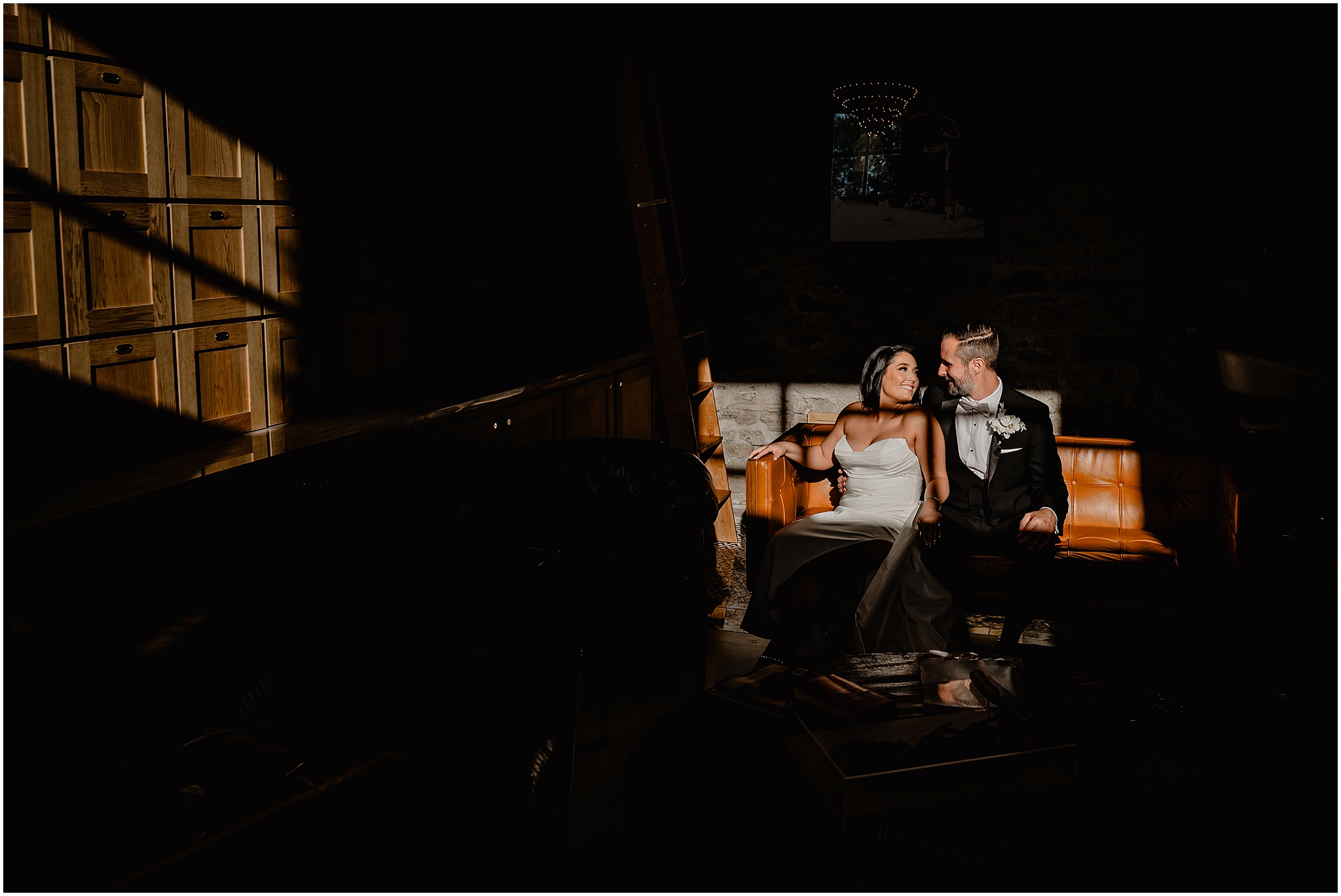 bride and groom sit on leather couch in sunlight streaming into space at The Logan Inn