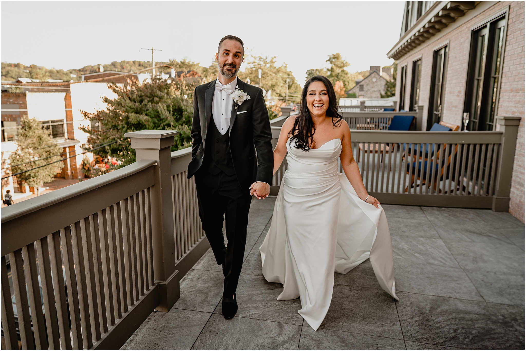 couple holds hands walking across patio balcony at The Logan Inn