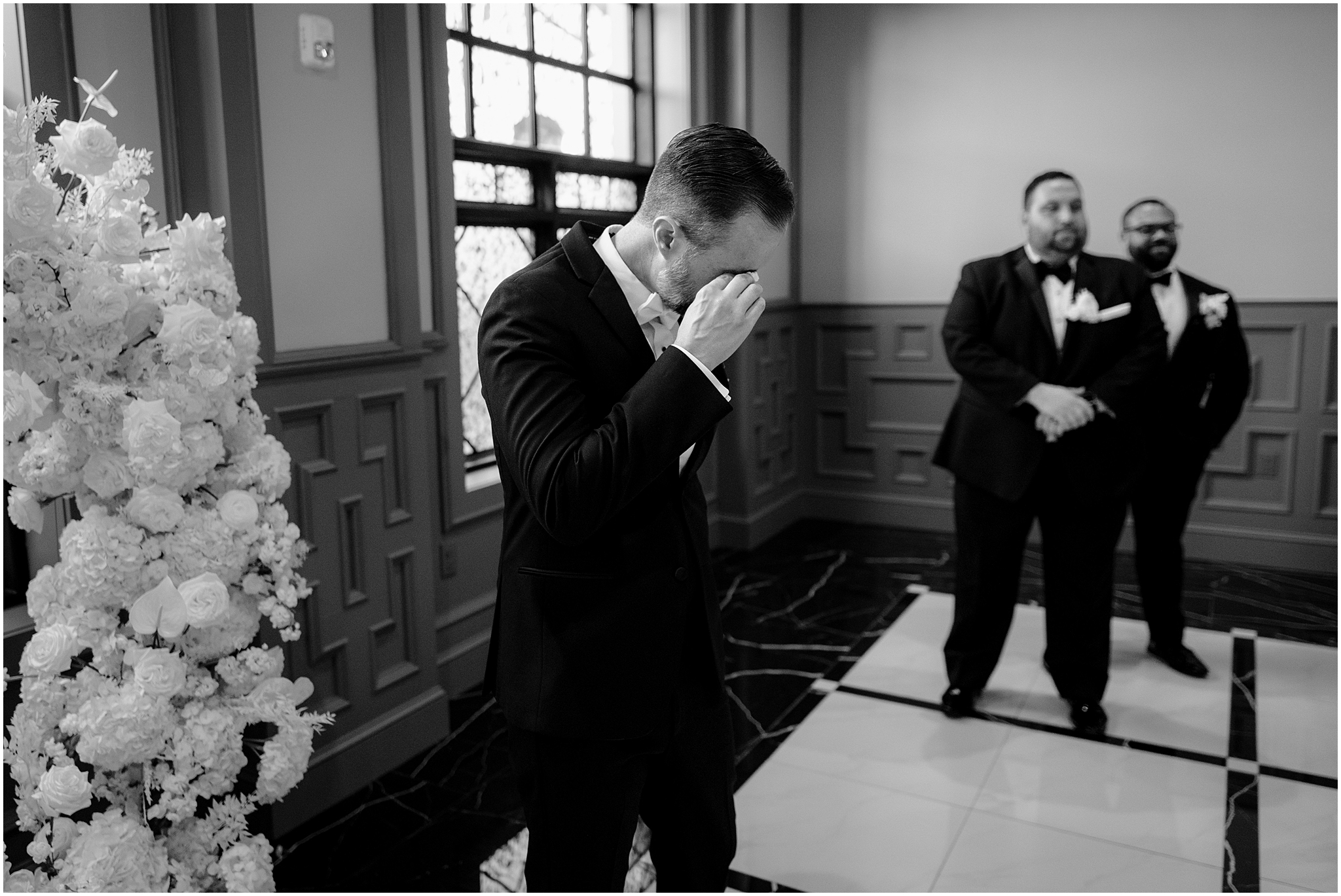 man cries next to spray of white flowers for ceremony in New Hope PA