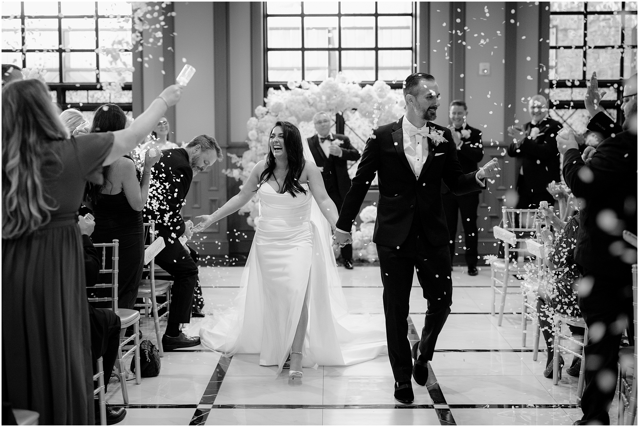 bride and groom cheer walking through confetti popped by guests