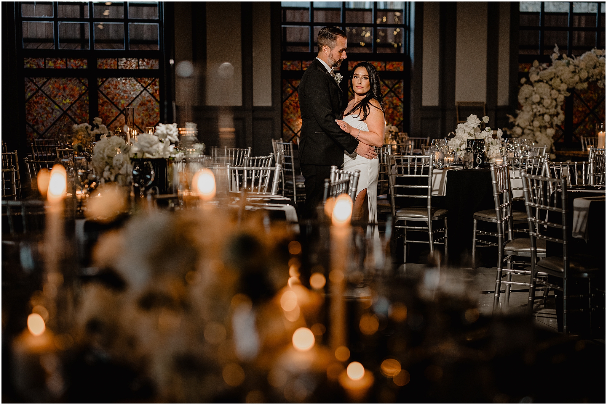 bride and groom hug in ballroom at The Logan Inn surrounded by white flowers and silver chivari chairs 