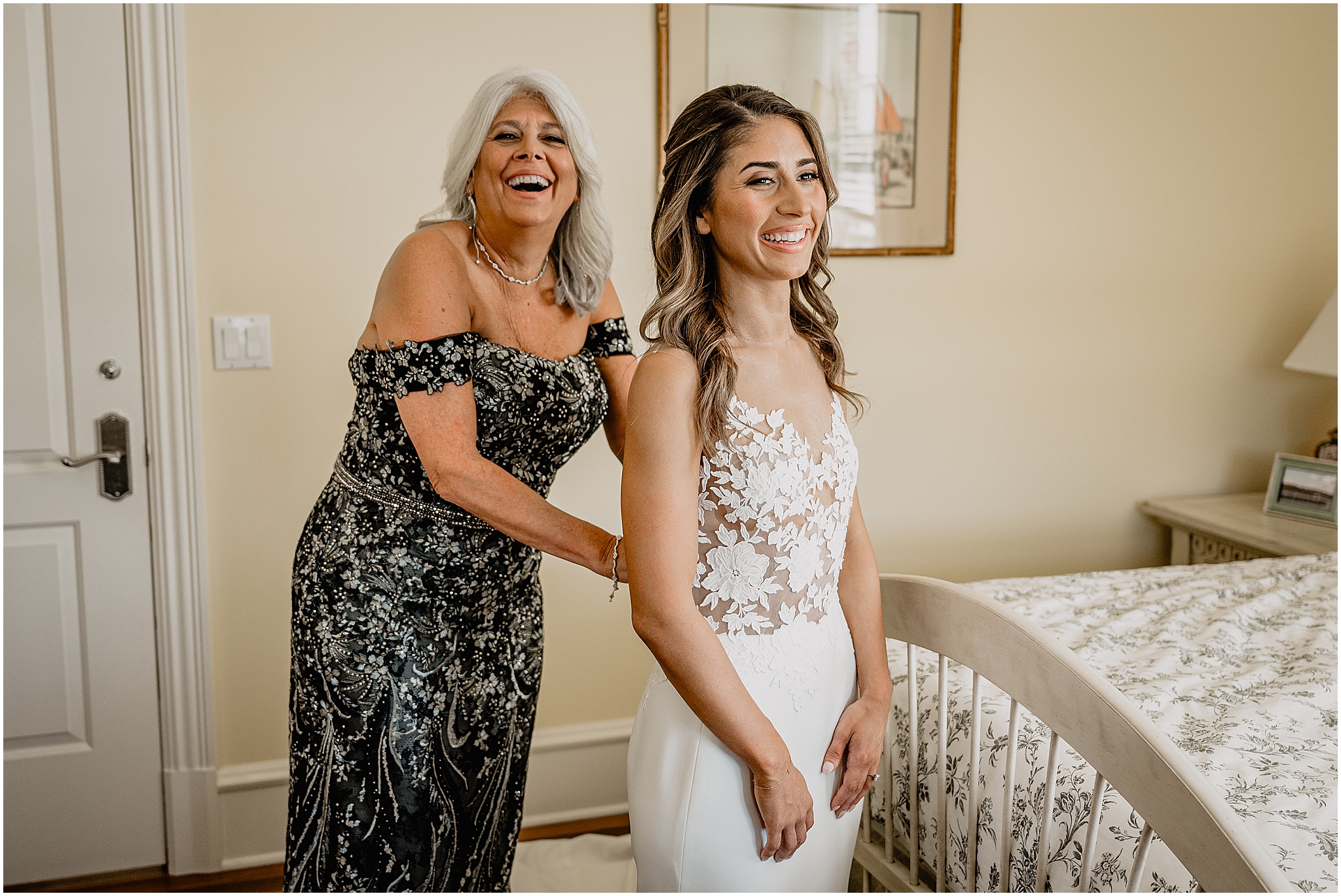 mother in black and gold gown helps bride into wedding dress