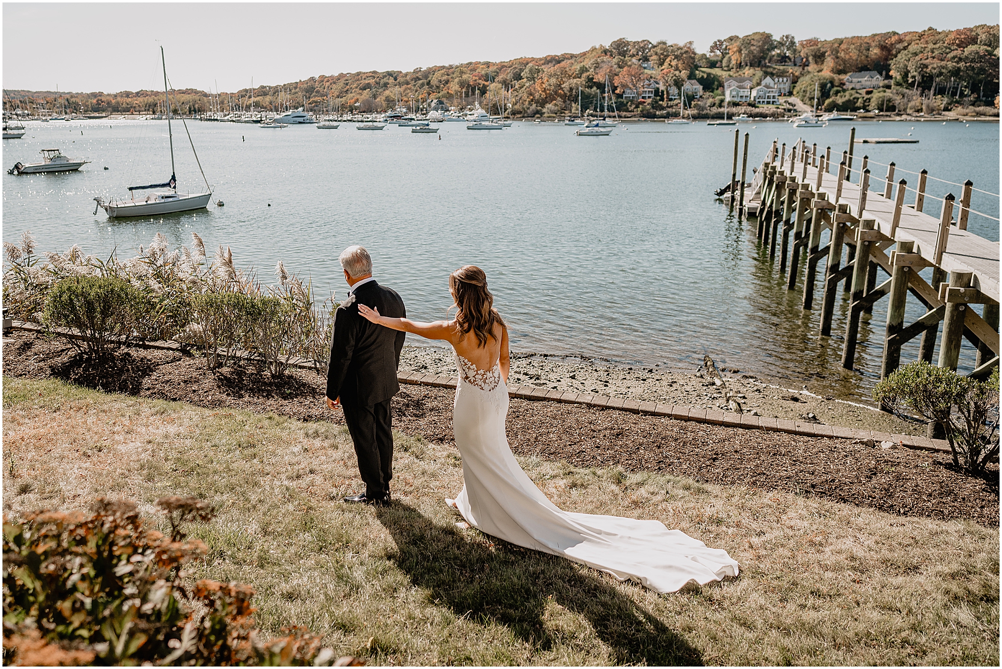 bride reaches to tap dad's shoulder on lawn of the Waters Edge at Centerport