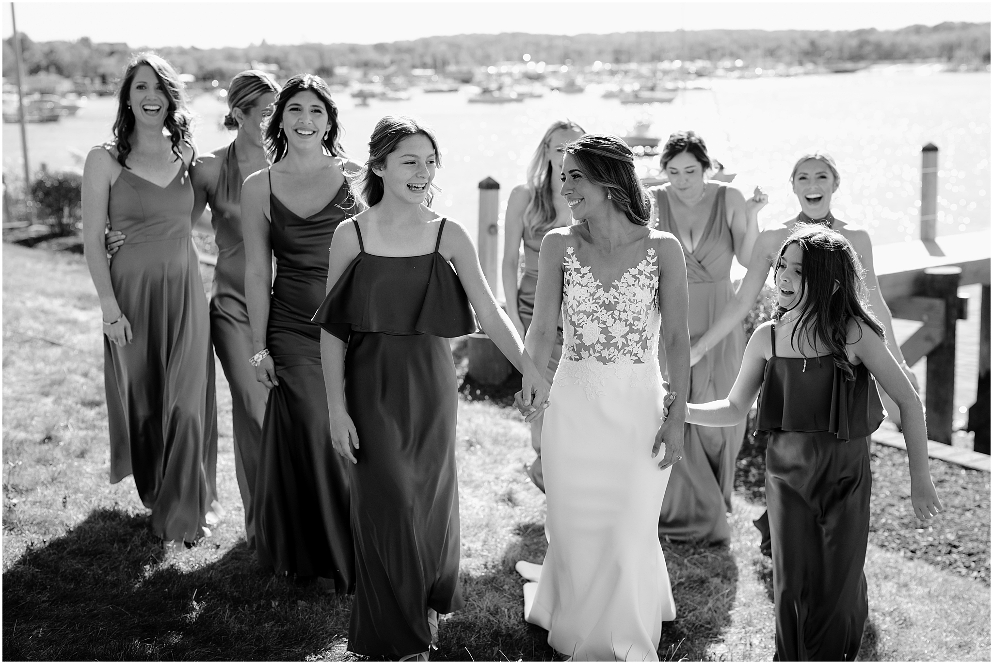 bride walks with bridesmaids and holds hands with junior bridesmaids on lawn at the Waters Edge at Centerport