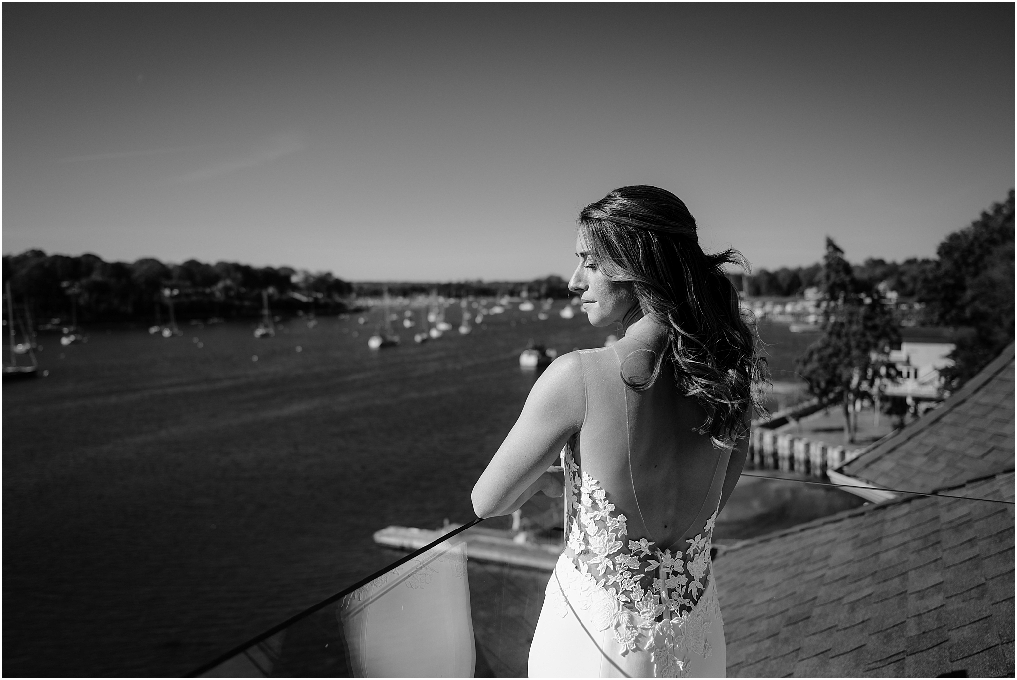 bride stands on balcony looking over her shoulder in wedding gown at the Waters Edge at Centerport