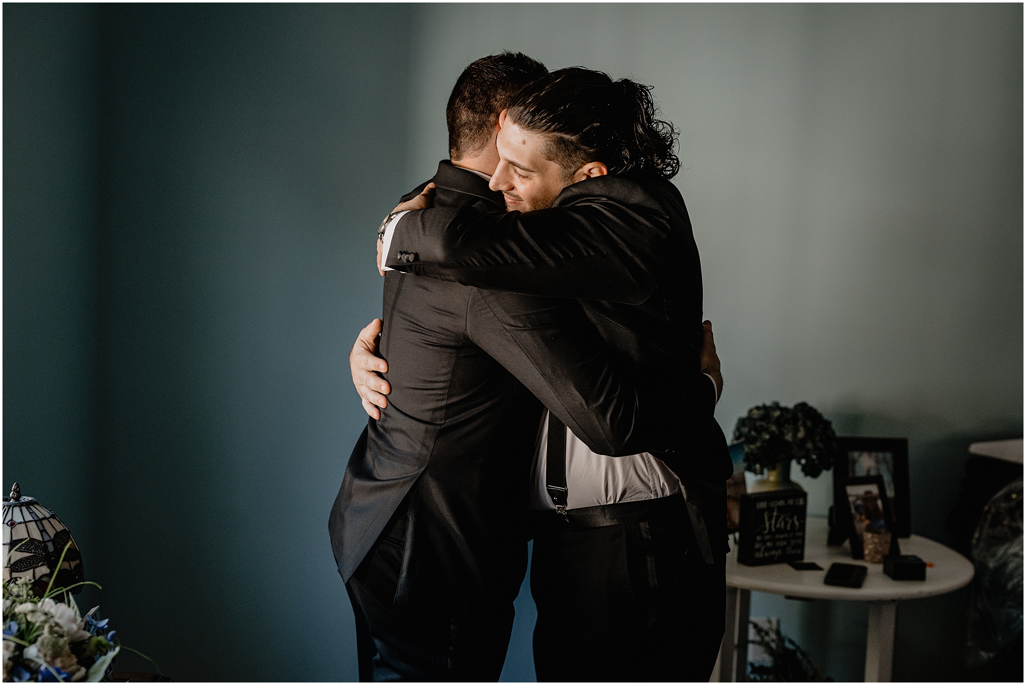 groom hugs groomsman during prep for NY wedding day on Long Island