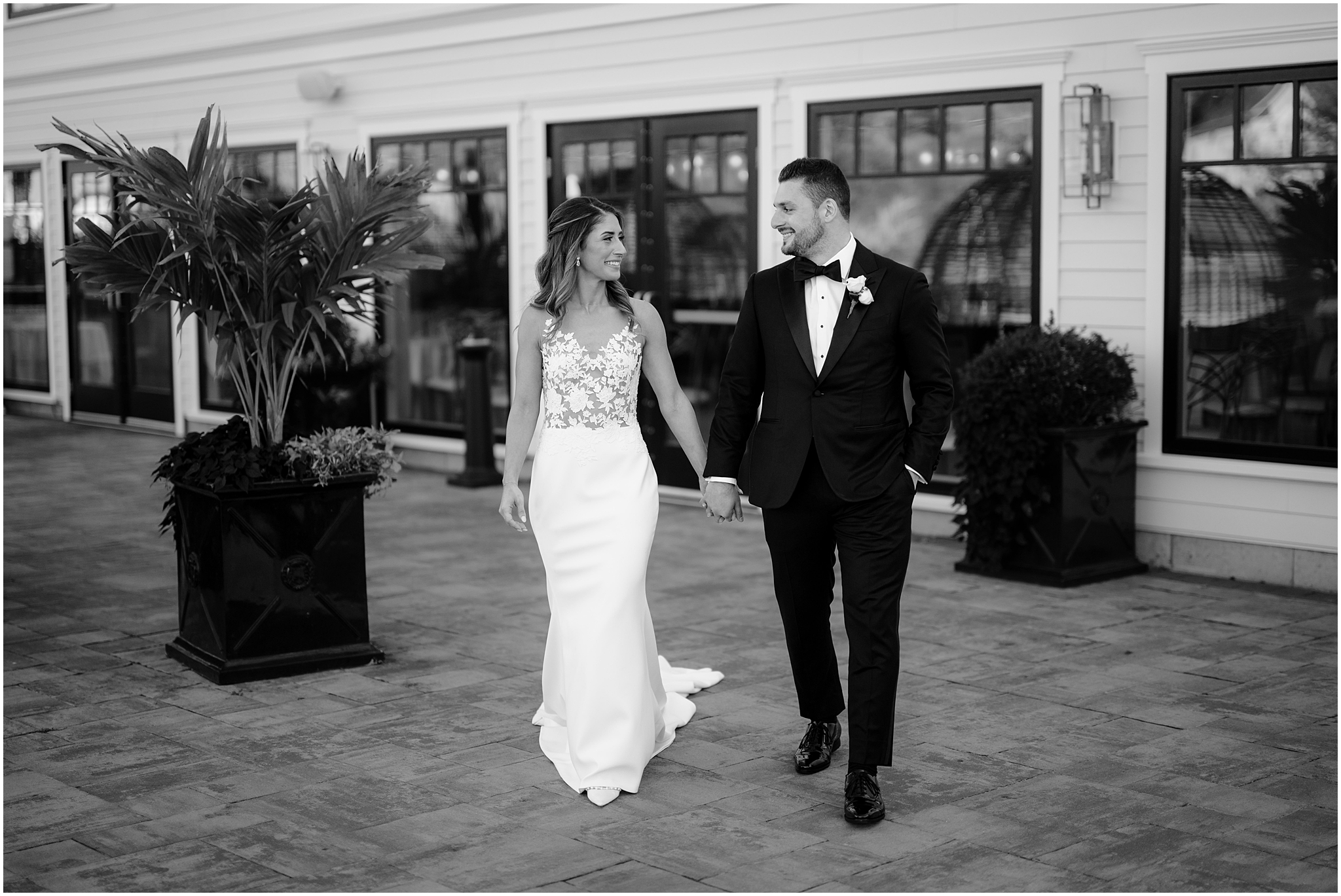 bride and groom hold hands walking on patio at the Waters Edge at Centerport