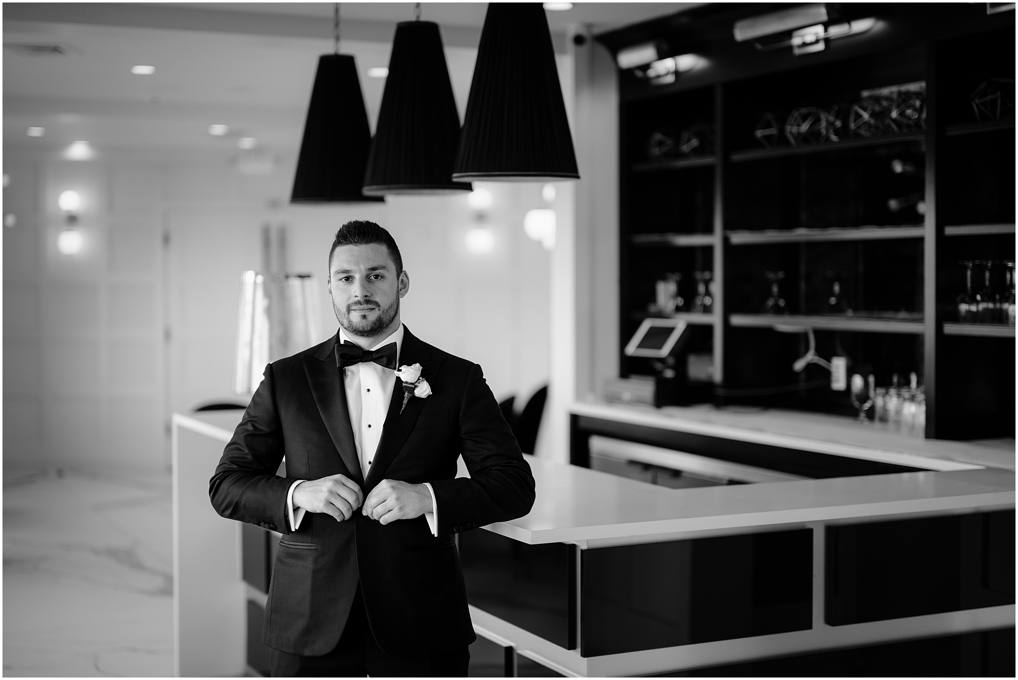 groom buttons up suit jacket standing near bar inside the Waters Edge at Centerport