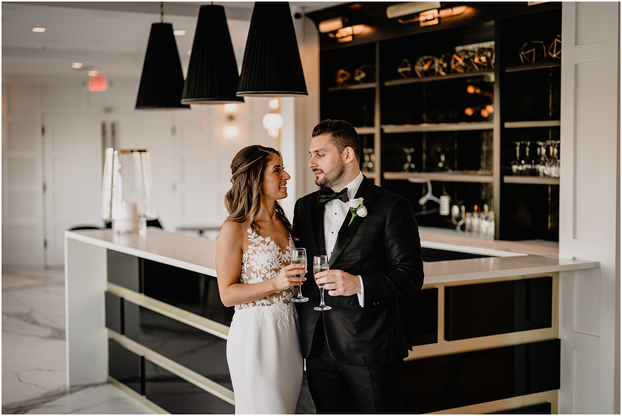 bride and groom smile toasting glasses of champagne in the bar at the Waters Edge at Centerport