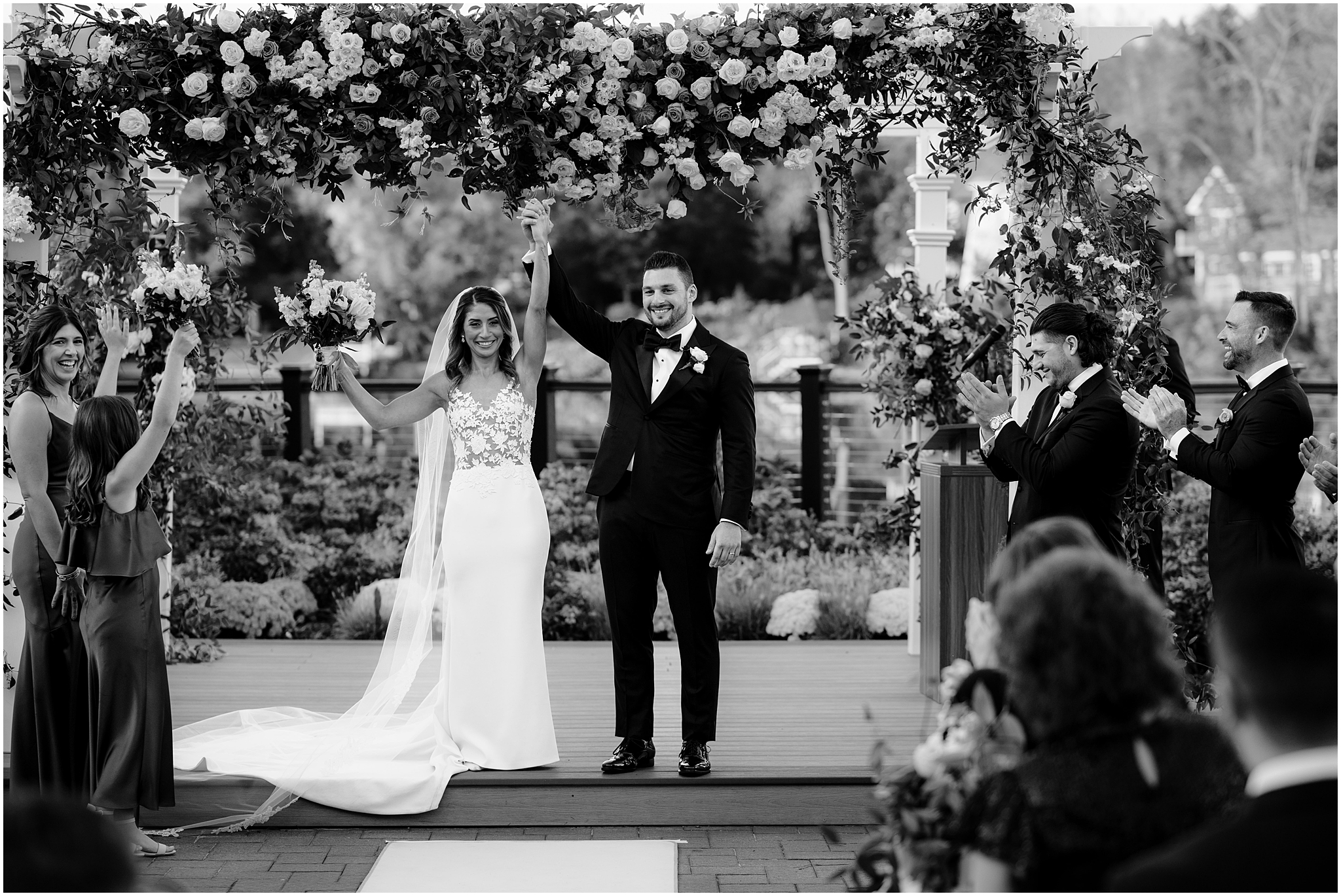 newlyweds hold hands cheering under arbor at the Waters Edge at Centerport