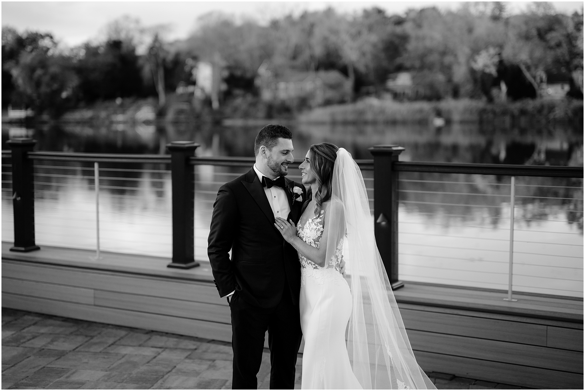 newlyweds hug on patio at the Waters Edge at Centerport smiling at each other