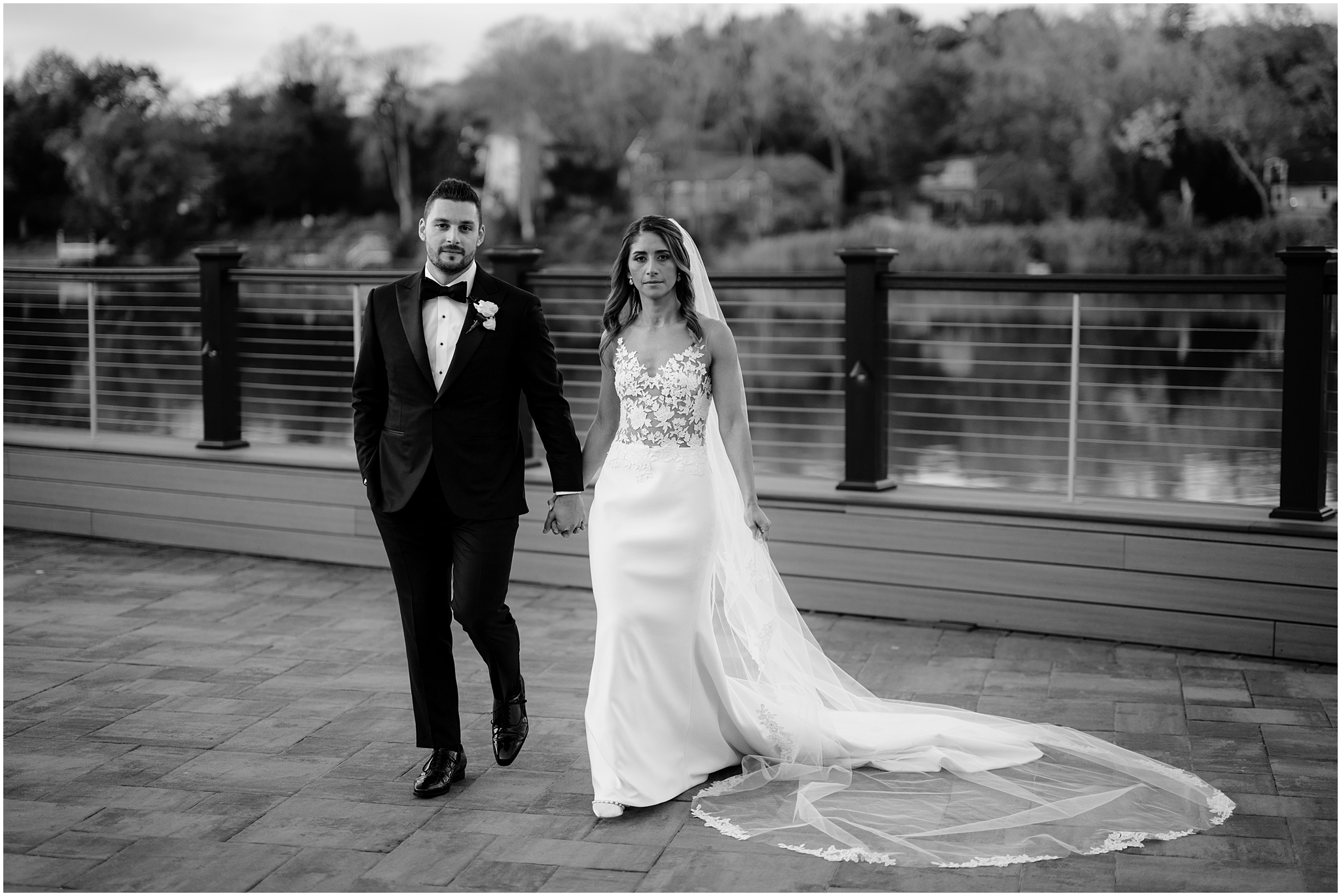 bride and groom hold hands walking on stone patio at the Waters Edge at Centerport