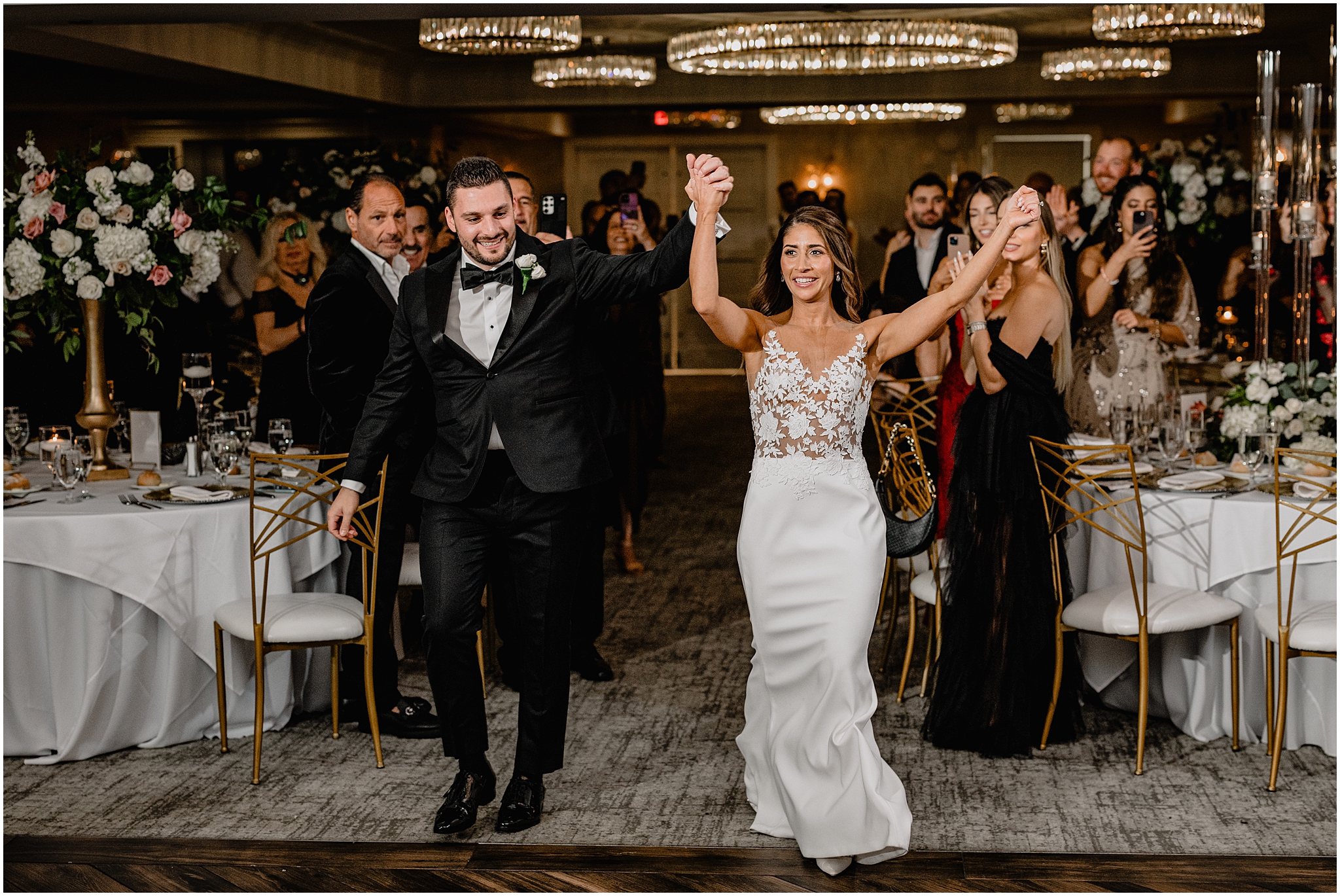 newlyweds cheer walking into reception in ballroom at the Waters Edge at Centerport