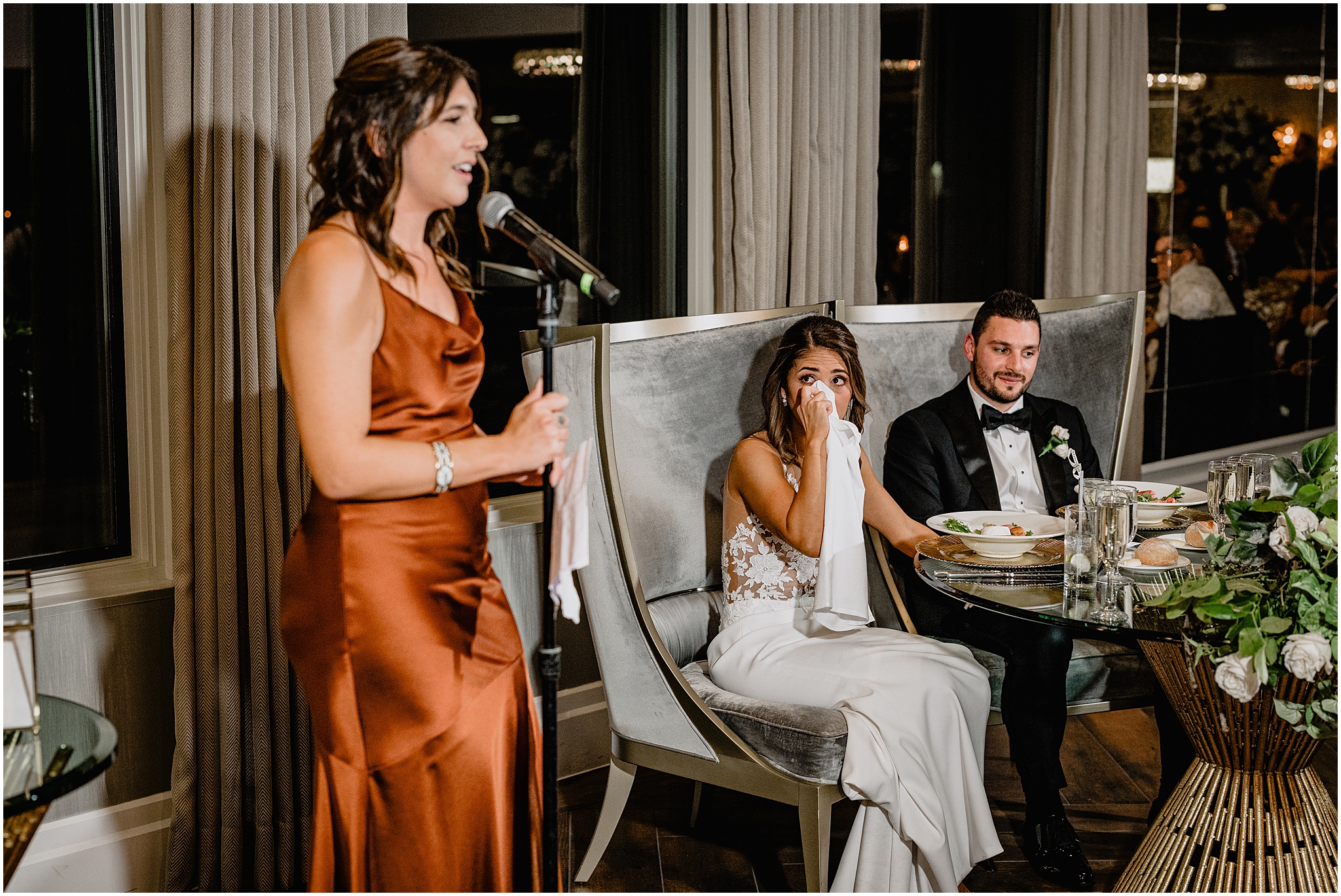 bride cries while bridesmaids in orange gown reads speech during Long Island wedding reception