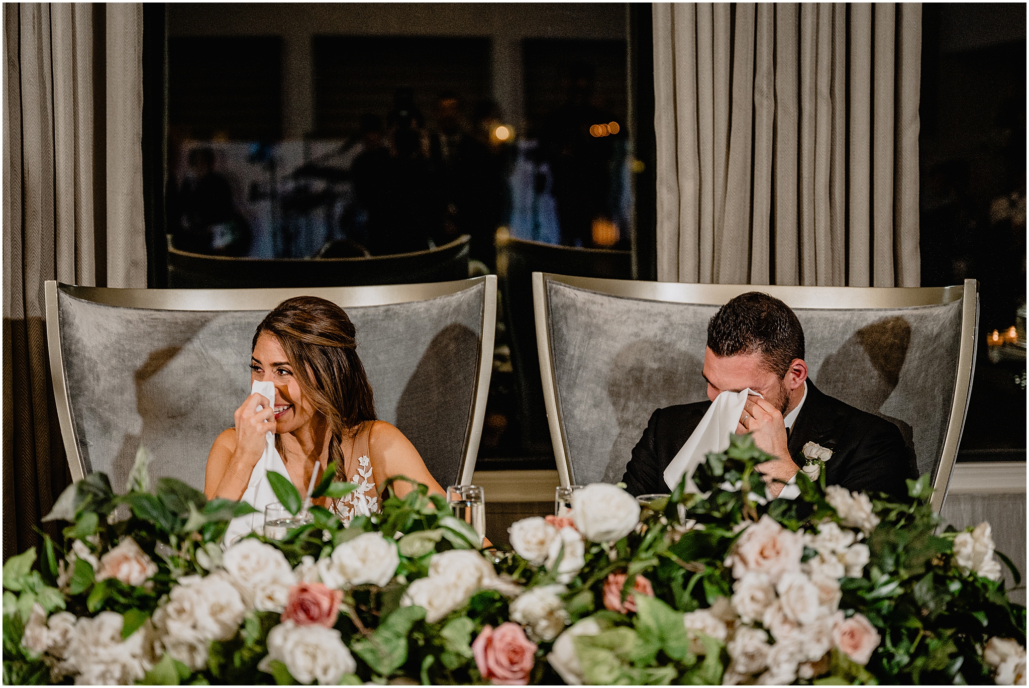 bride and groom cry during speeches sitting in oversize chairs during Long Island wedding reception