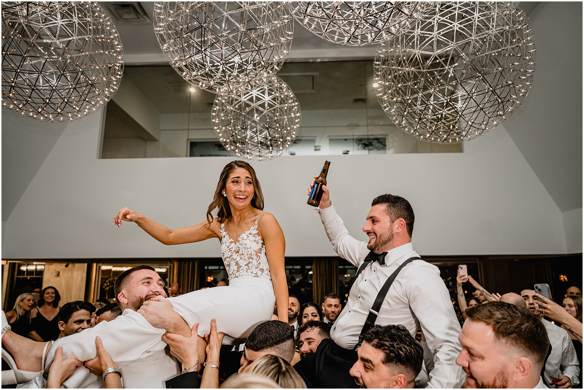 wedding guests lift up bride and groom during dances at Long Island wedding reception