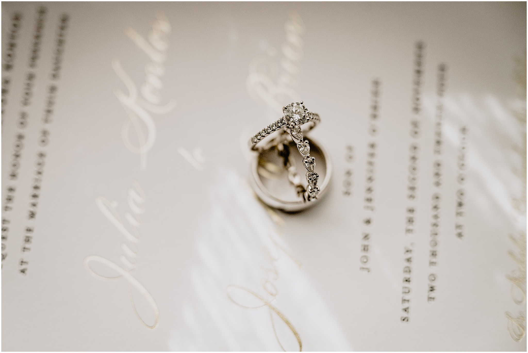 diamond wedding band stacked on top of man's wedding ring on invitation suite 