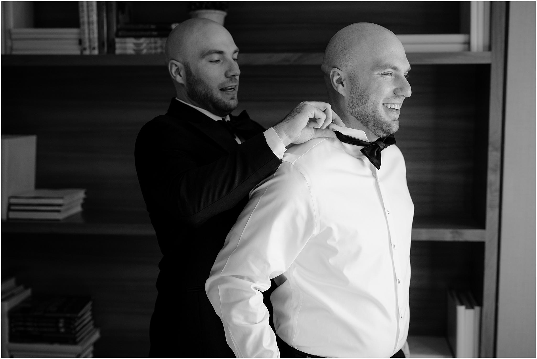groomsman adjusts bowtie for groom in library of NJ house