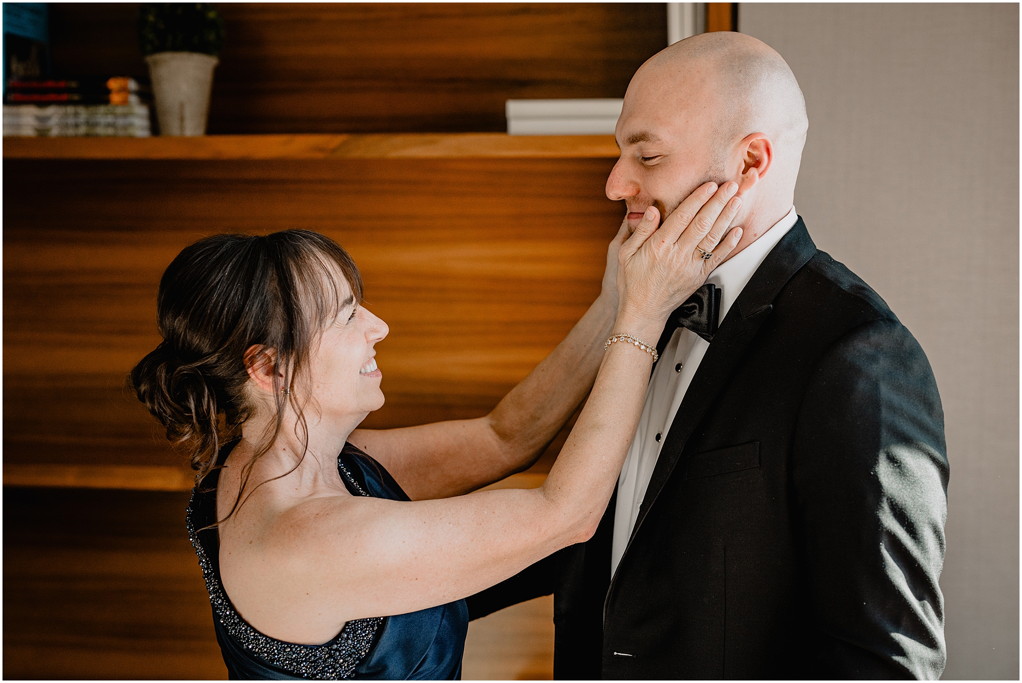 mother smiles holding groom's chin during wedding day prep in New Jersey 