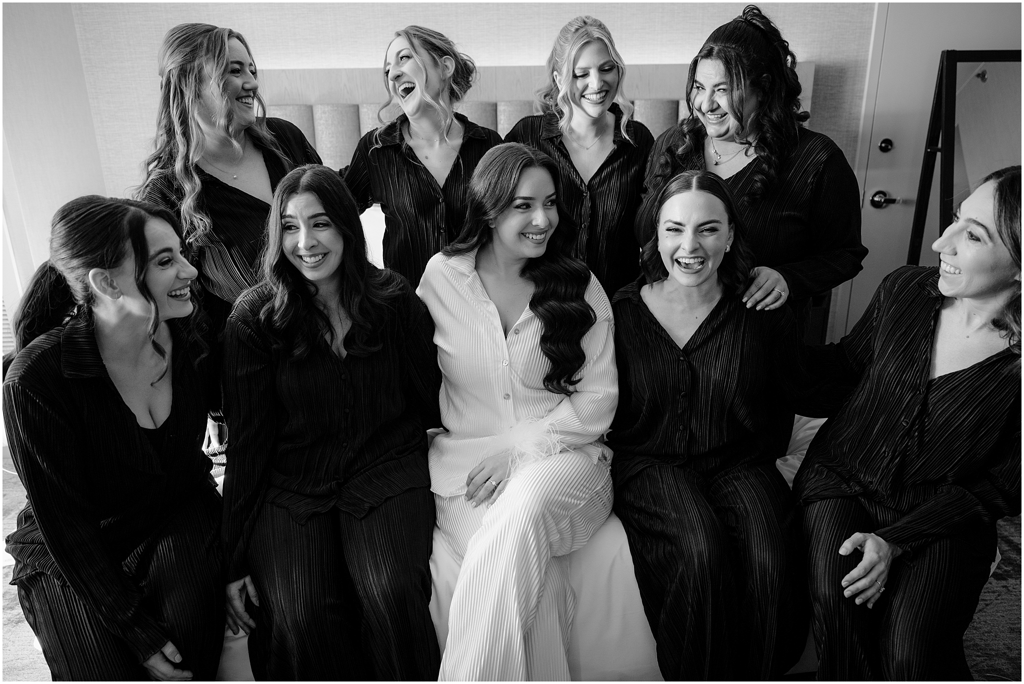 bride smiles laughing with bridesmaids in matching black pajamas 