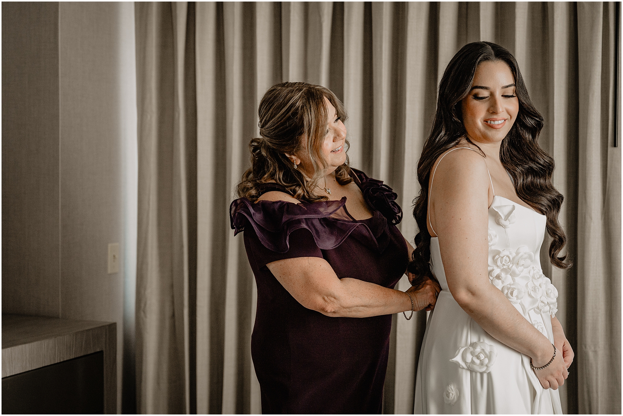 mother helps bride into wedding dress during Jersey City prep