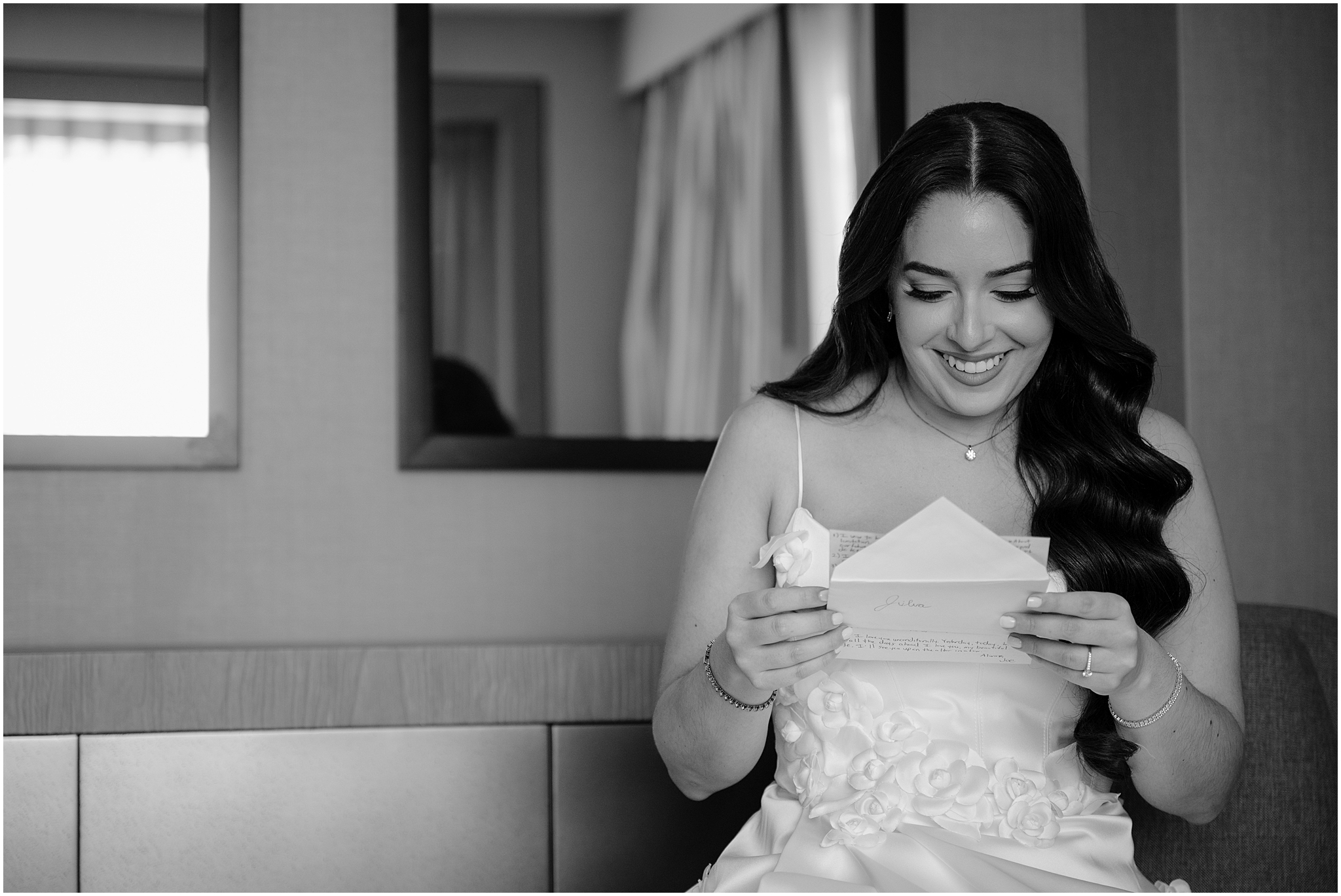 bride reads letter from groom sitting on couch in Jersey City hotel