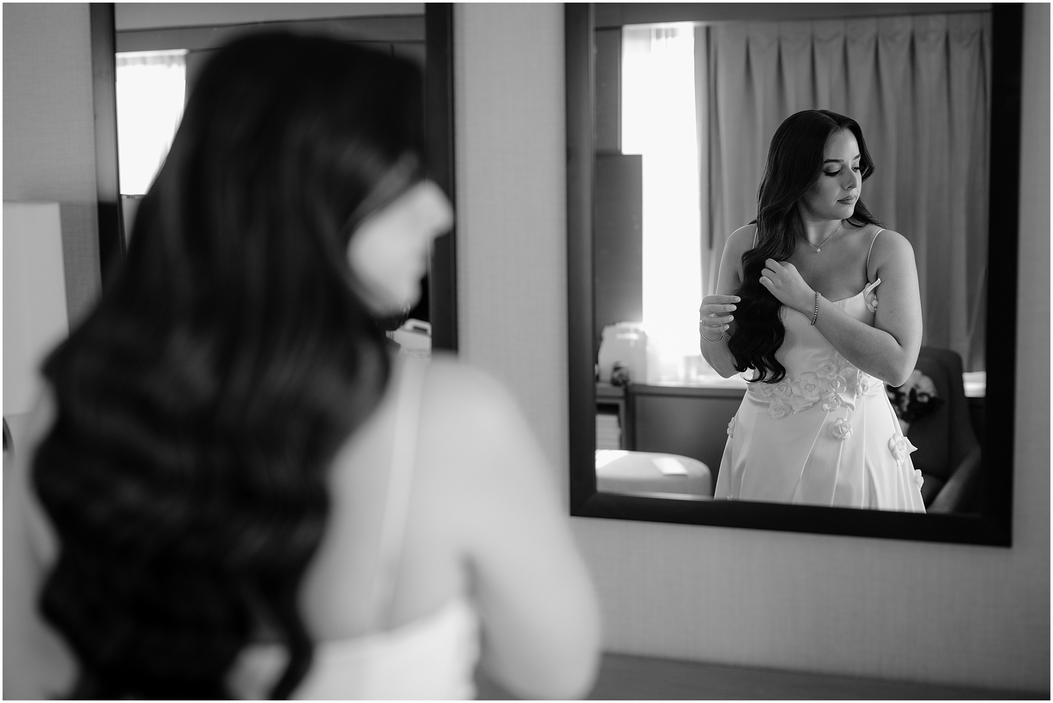 bride brushes hands through curls in reflection of mirror during Jersey City wedding day prep
