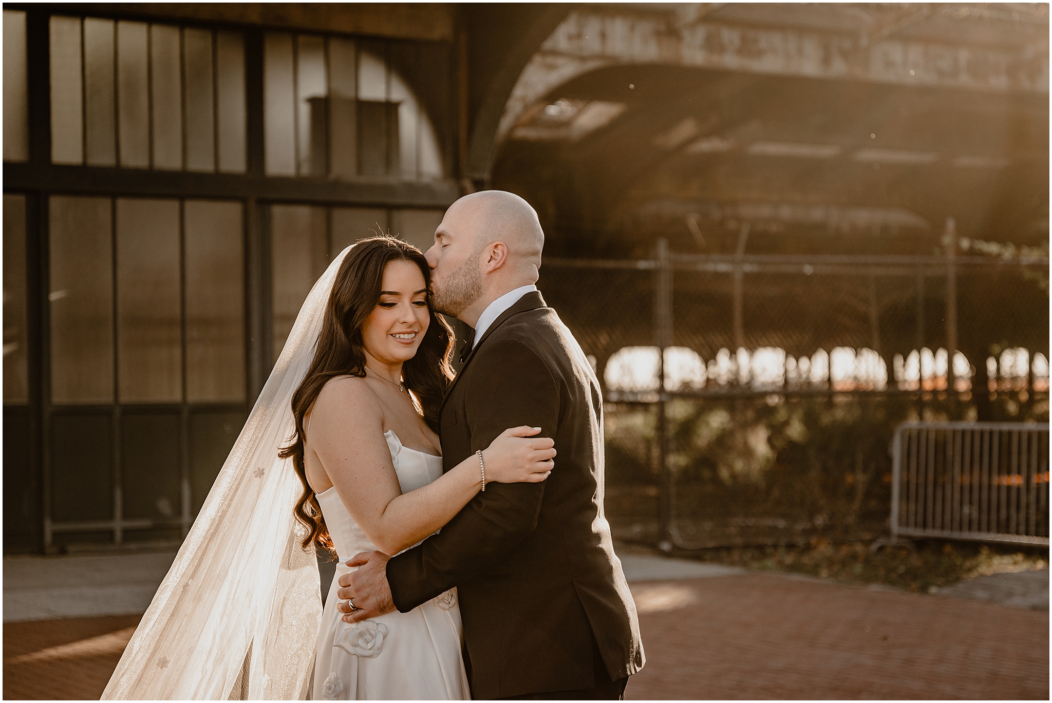 groom hugs bride to him kissing her forehead in front of the Liberty House Restaurant