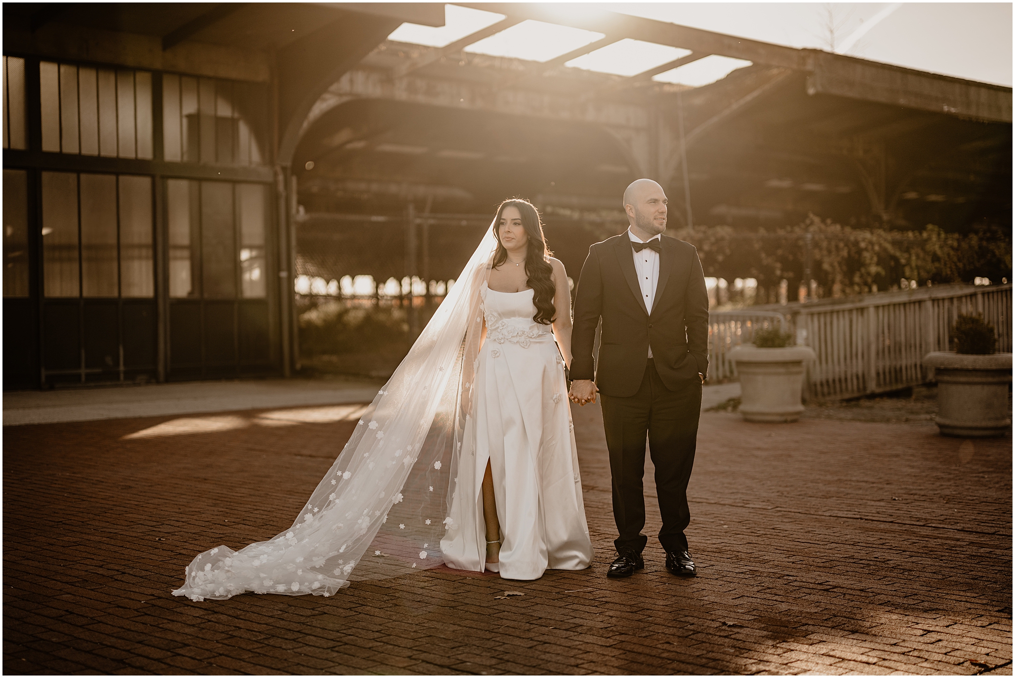 bride and groom hold hands at sunset in front of the Liberty House Restaurant