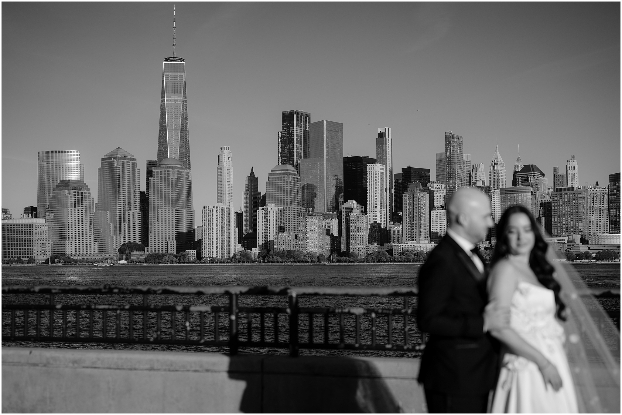 bride and groom hug in front of Manhattan skyline in Jersey City 