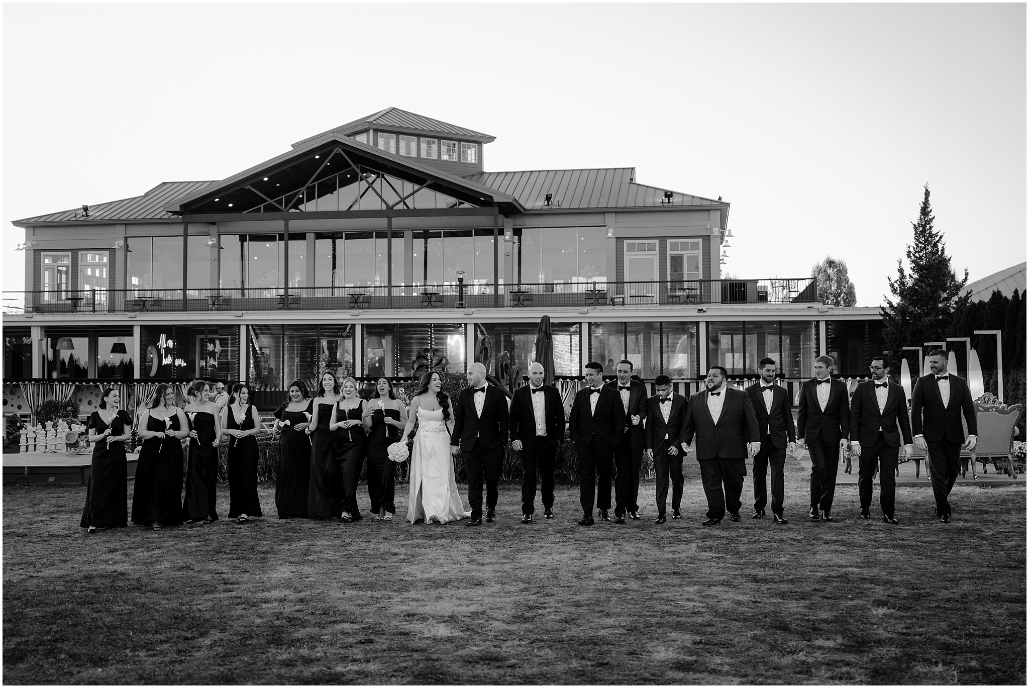newlyweds hold hands walking with bridal party in front of the Liberty House Restaurant