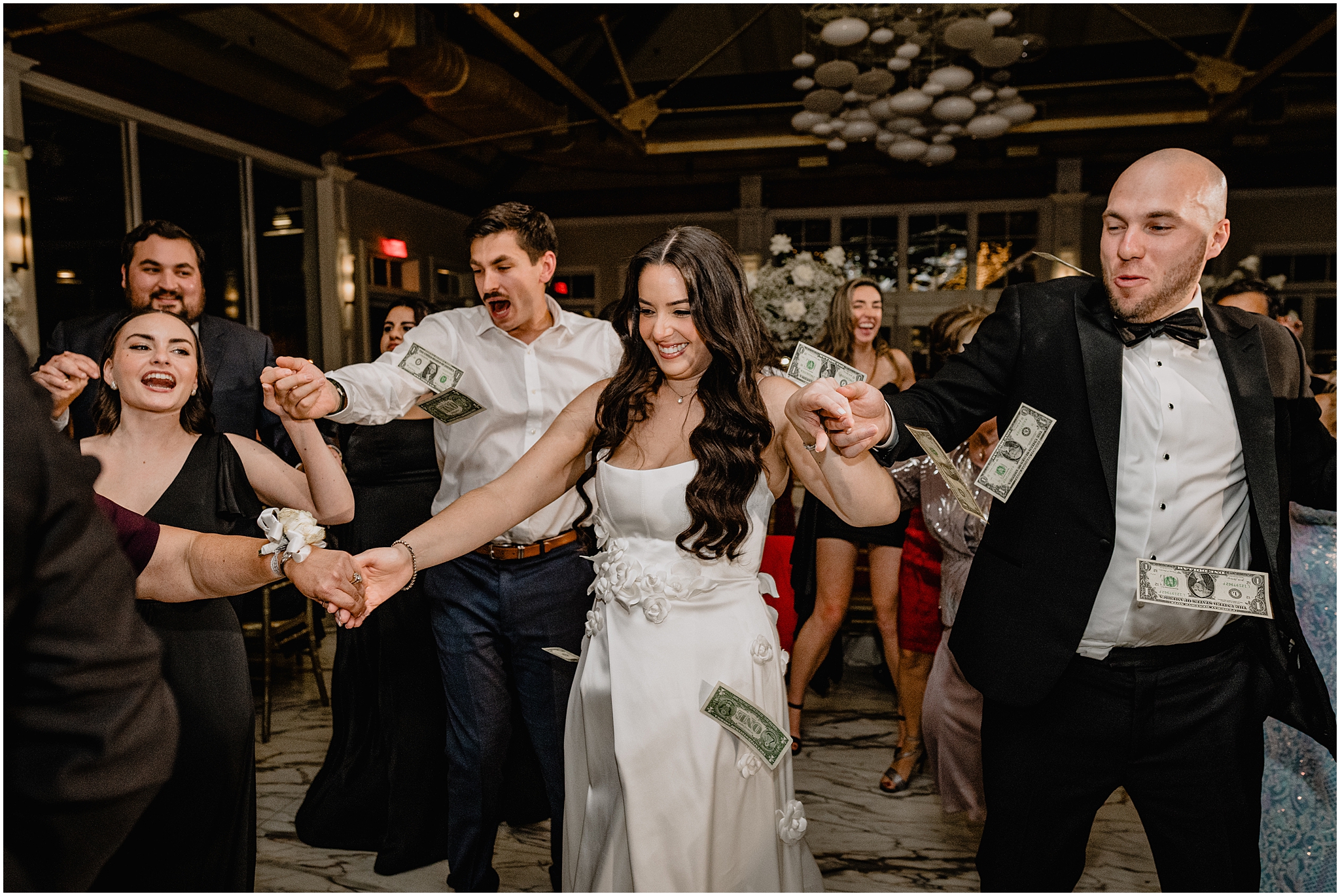 bride and groom dance while money is thrown in their dance circle