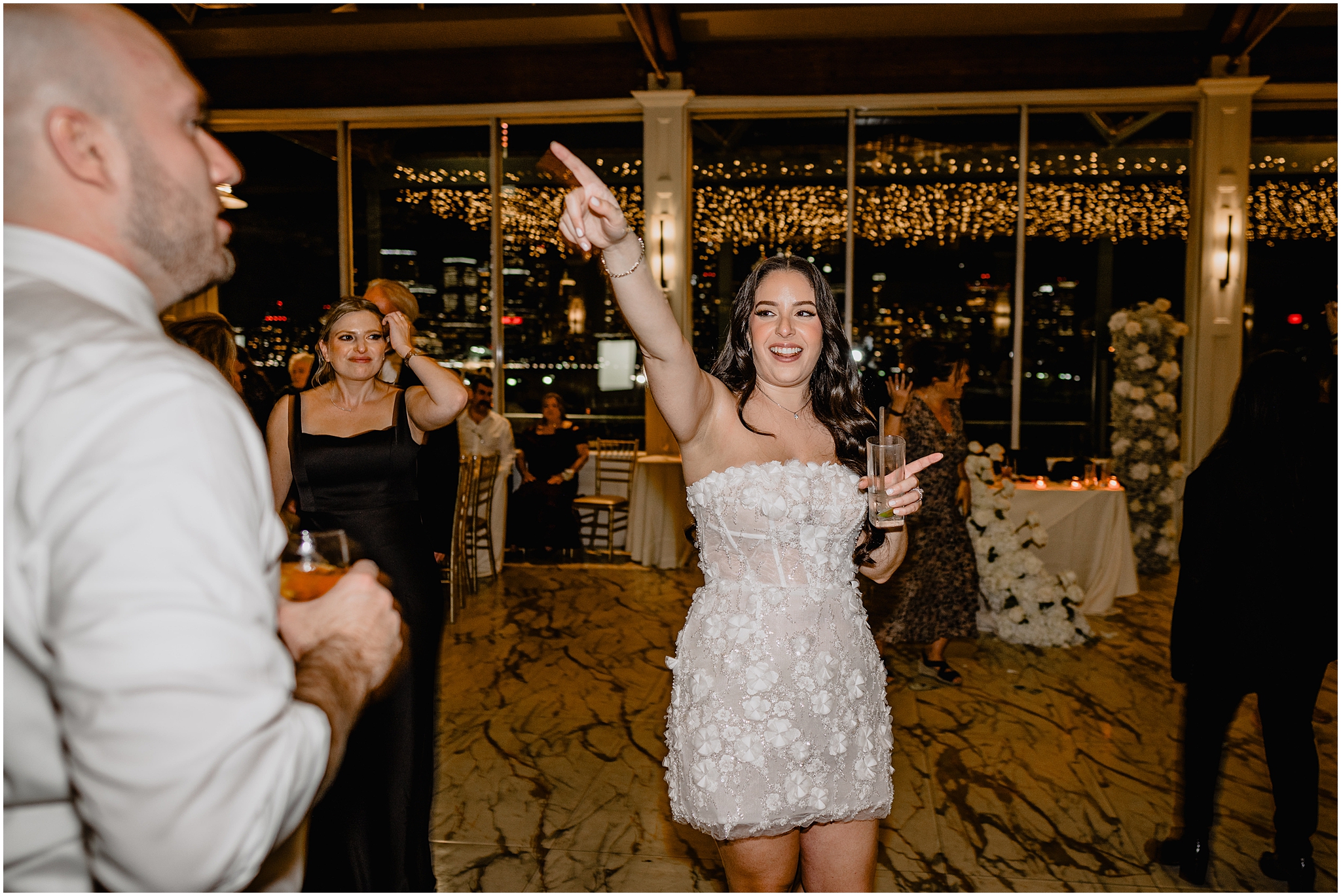 bride cheers in short white floral dress on dance floor at the Liberty House Restaurant