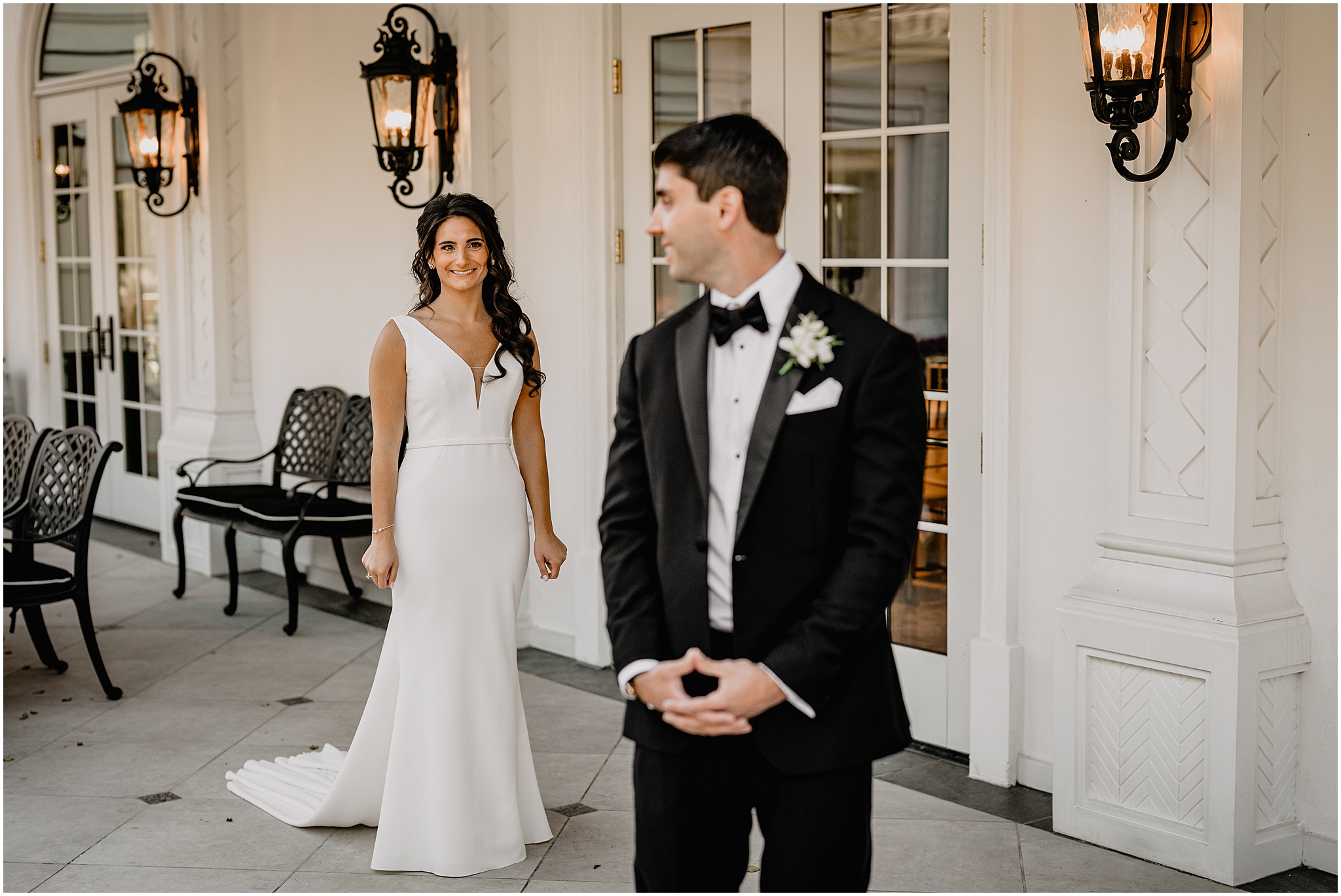 bride smiles and approaches groom for first look on patio at The Shadowbrook at Shrewsbury